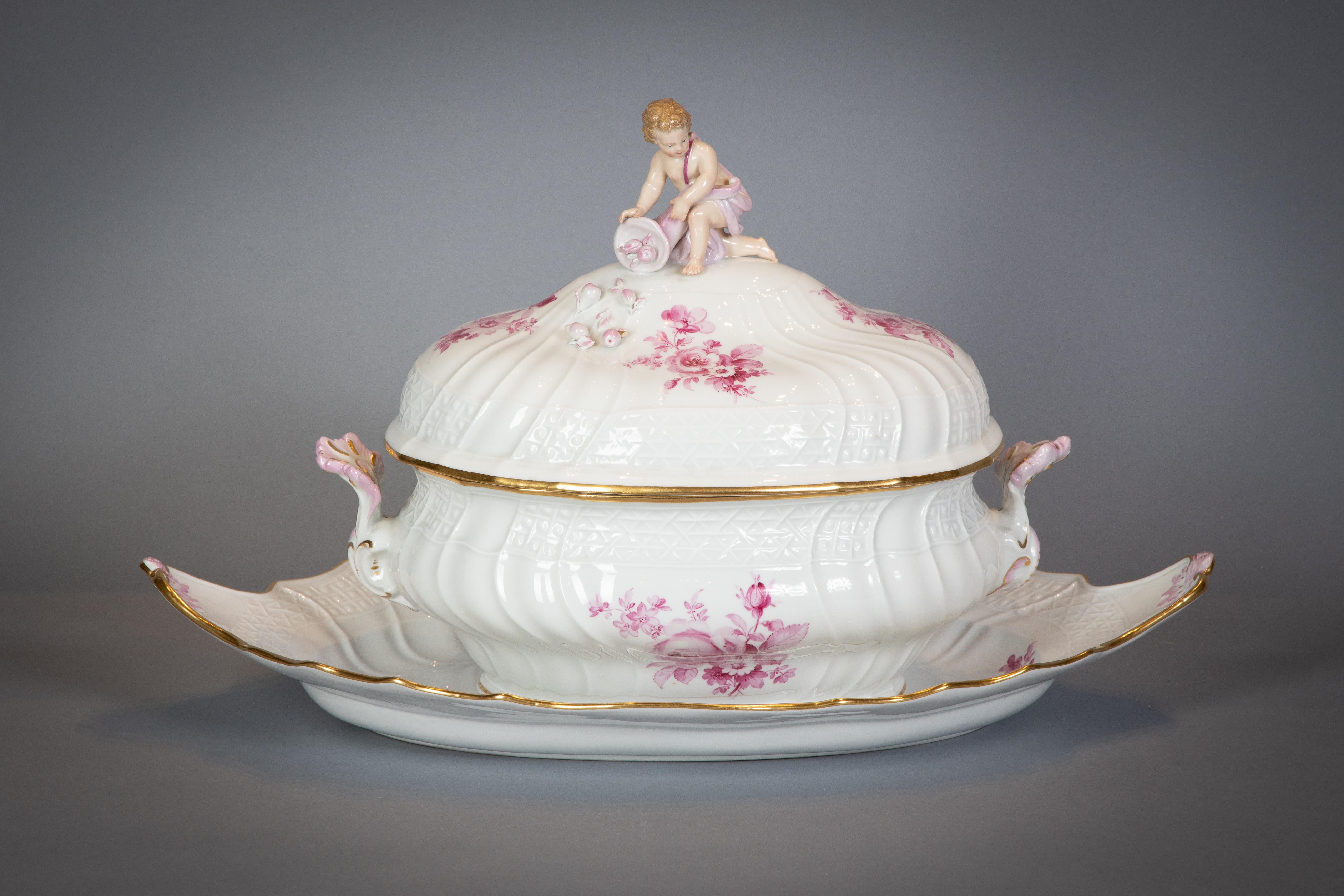 Delicately painted in German taste with rose camaieu flowers, the cavetto with spiral molding insterspersed with flowers, and the border with variations of basket weaving. Covered tureen and stand, pair of entree dishes, bowl, sauceboat, fish