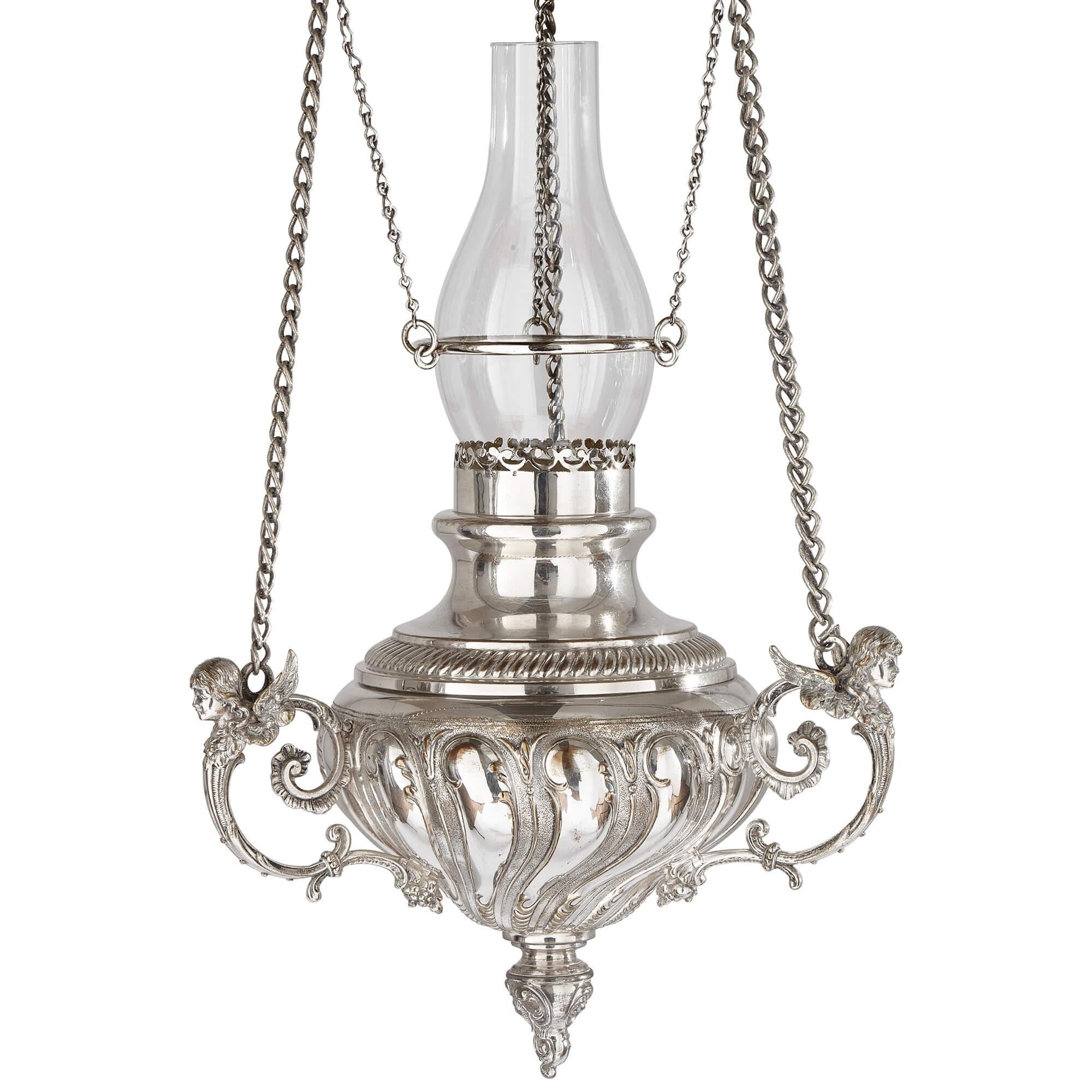 Grande lanterne suspendue allemande en métal argenté par WMF
Allemand, c.1920
Hauteur 90 cm, diamètre 24 cm

Constituée d'un fleuron rond et pointu à godrons suspendu par des chaînes en forme de ruban et surmonté d'un luminaire ouvert, cette pièce
