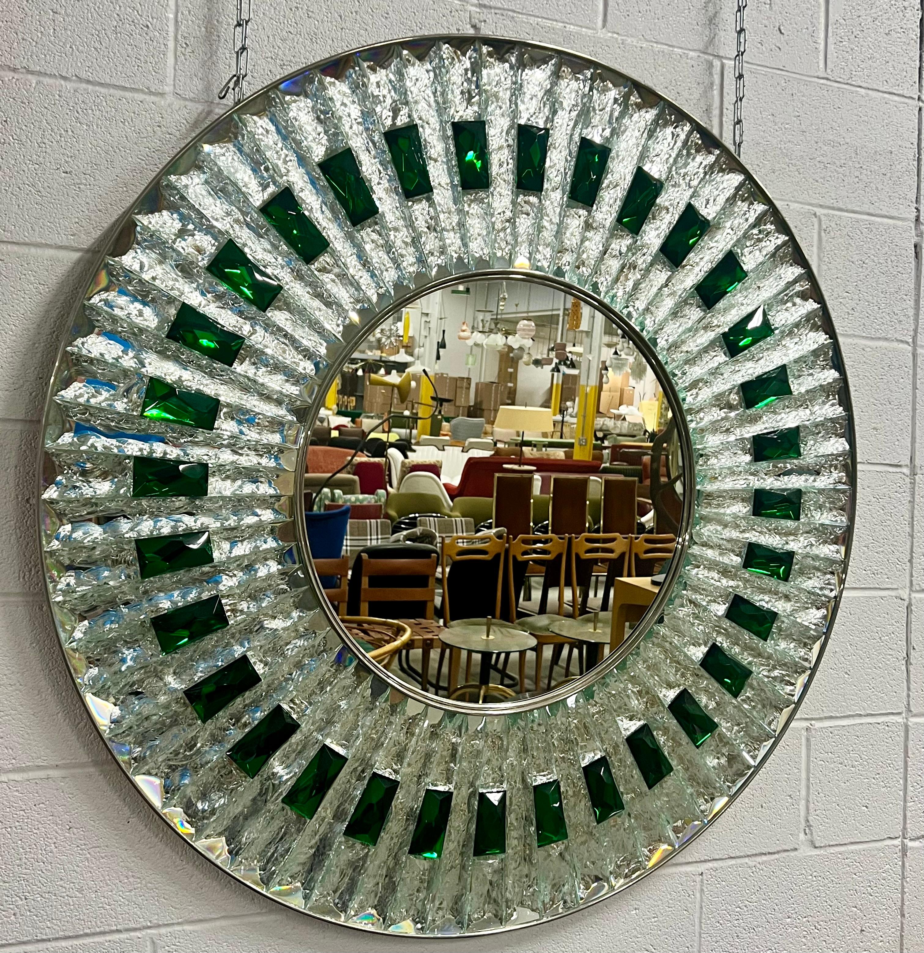 This is a beautiful one of a kind large Ghiro mirror.
Each piece is hand-cut and chiseled emerald green and clear colored crystals surround a central, circular mirror. 
