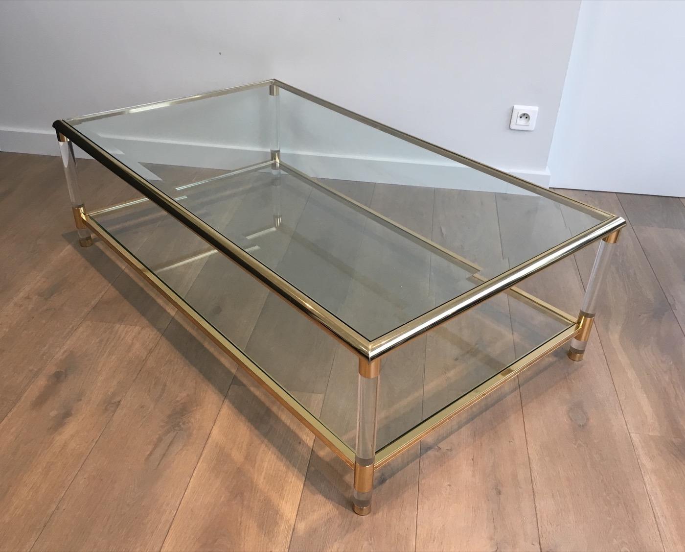 This large coffee table is made of gold gilt nickel with round Lucite legs. This cocktail table has a great design with unusual rounded corners. It is French, circa 1970.