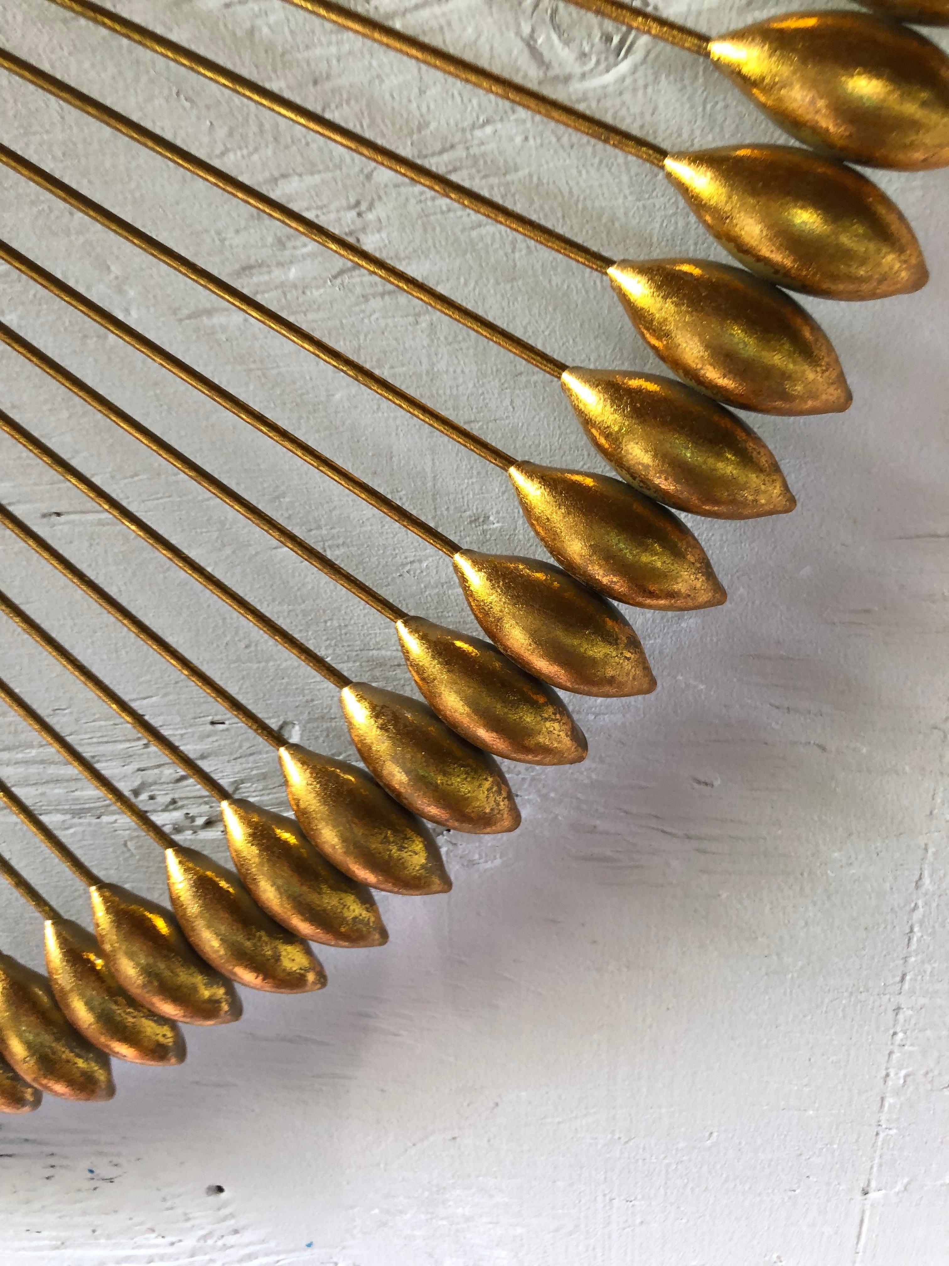 Striking designer gilded metal large round wall art resembling arrows artfully arranged in a circle.