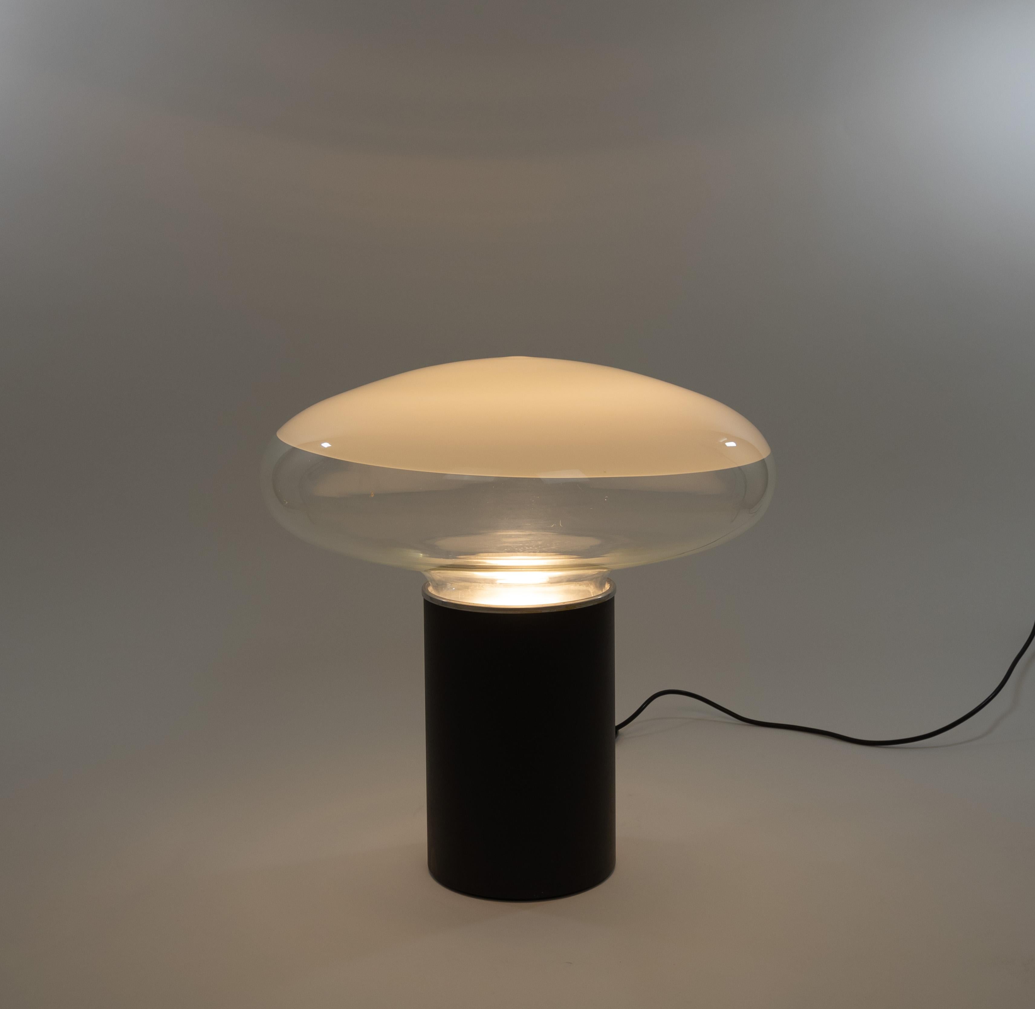 Large Gill table lamp designed by Roberto Pamio for Leucos in the 1960s.

The lamp consists of two main parts; the metal cylinder shaped base and a diffuser in glass that is partly transparant and partly white. The diffuser sits on an internal metal