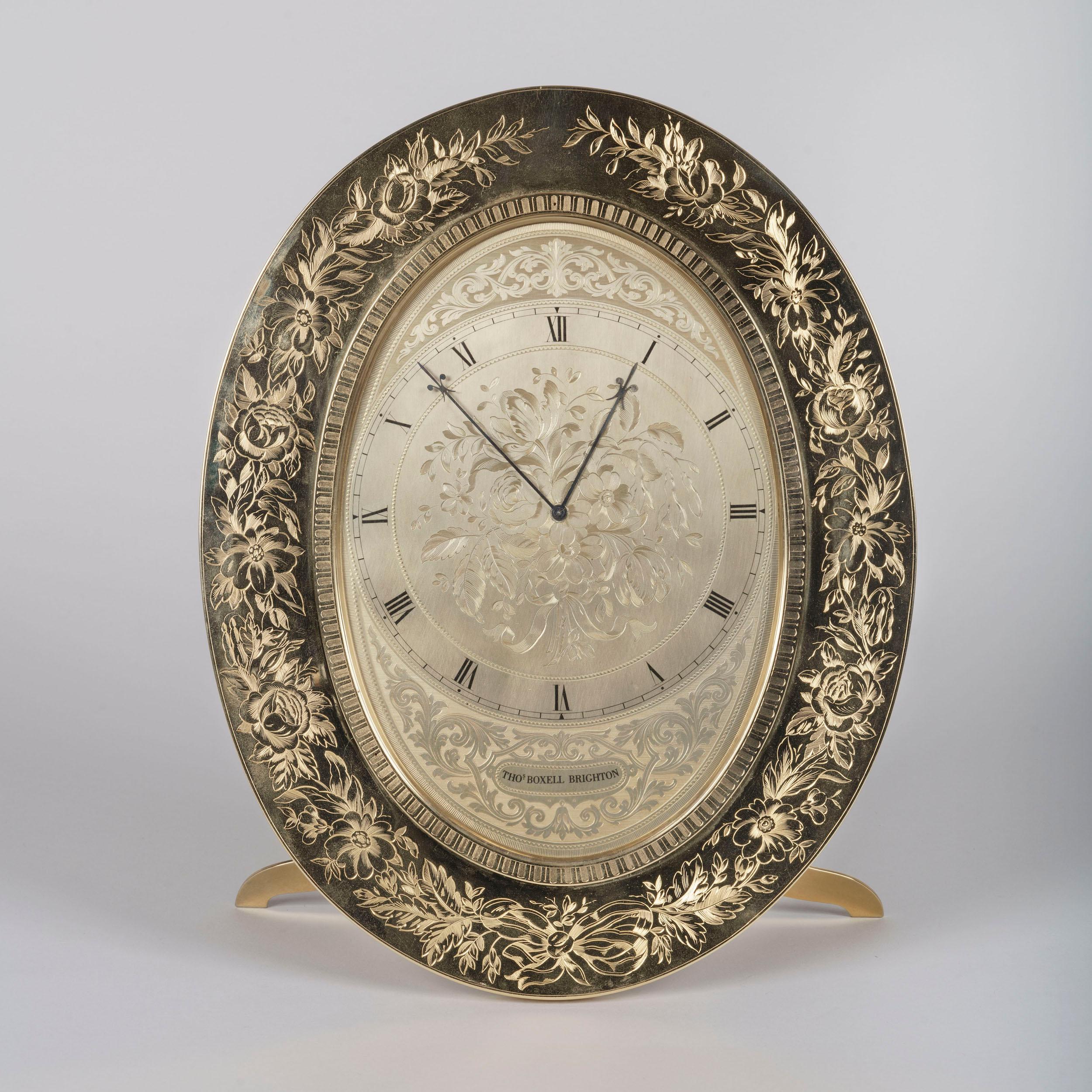 A large oval strut clock
By Thomas Cole

The case constructed from gilt brass and designed to be as thin as possible, finely engraved throughout, of substantial oval size, and supported by means of a fold-out foot, the outer frame with floral