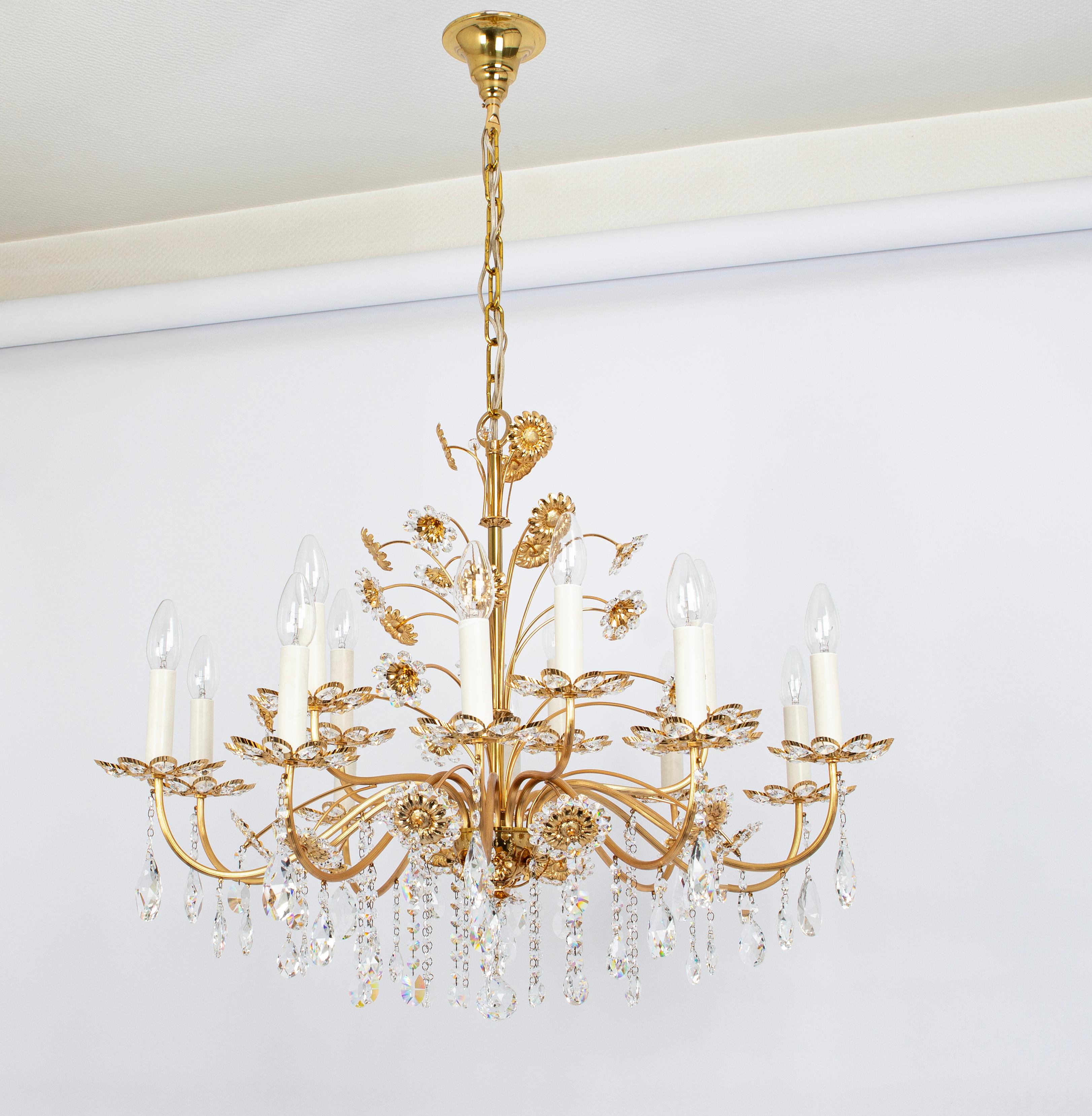 Enorme lampadario di metà secolo in ottone dorato con bicchieri di cristallo, realizzato da Palwa, Germania, produzione 1970-1979 circa.
Lo splendido lampadario ha tanti bellissimi cristalli sfaccettati (Swarovski) tagliati a mano a forma di fiori