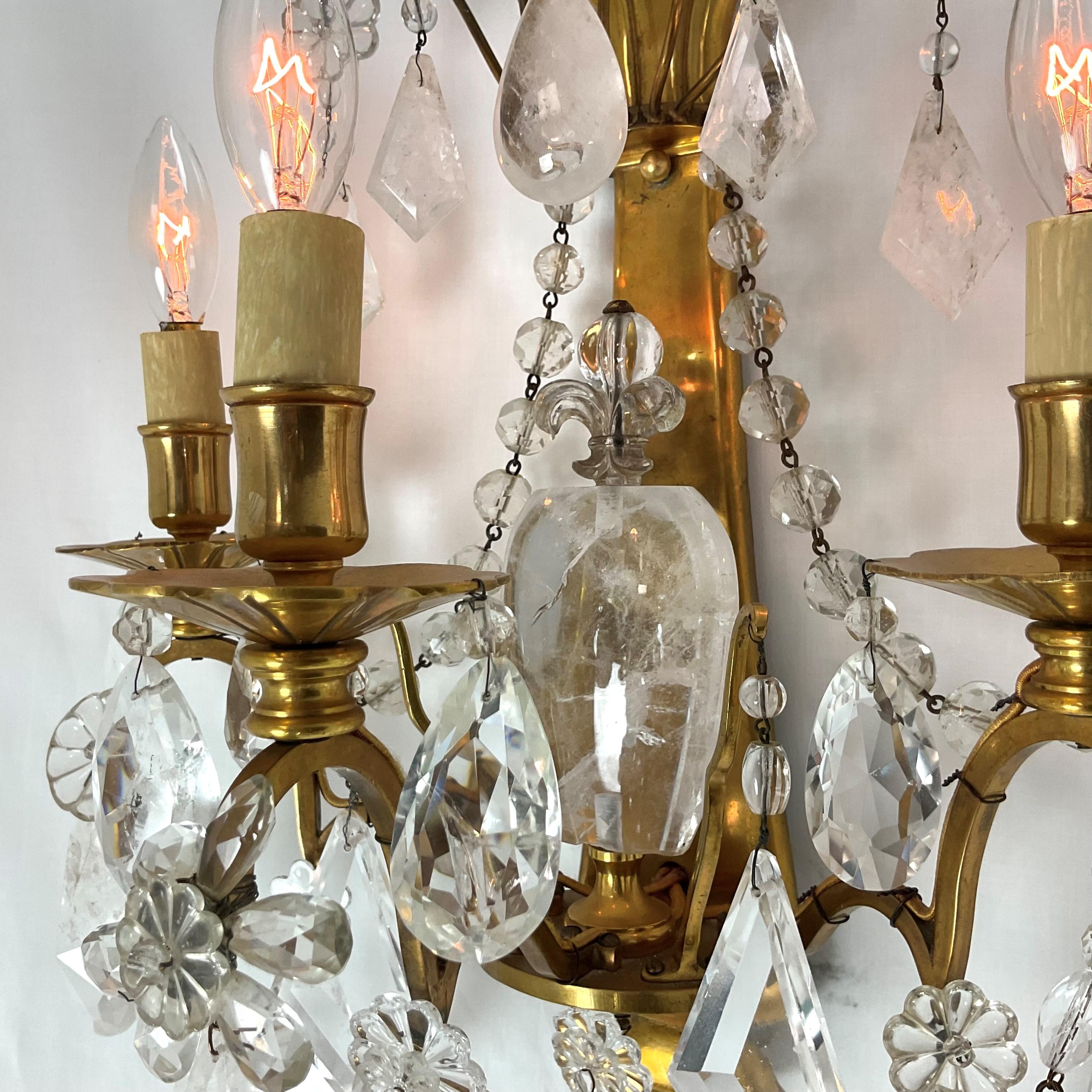 Gran e inusual pareja de apliques franceses de latón dorado. Colgantes de cristal de roca. Enorme pieza central de cristal de roca con una flor de tope. Estilo clásico francés. Calidad estupenda. Cada candelabro admite 3 bombillas candleabra