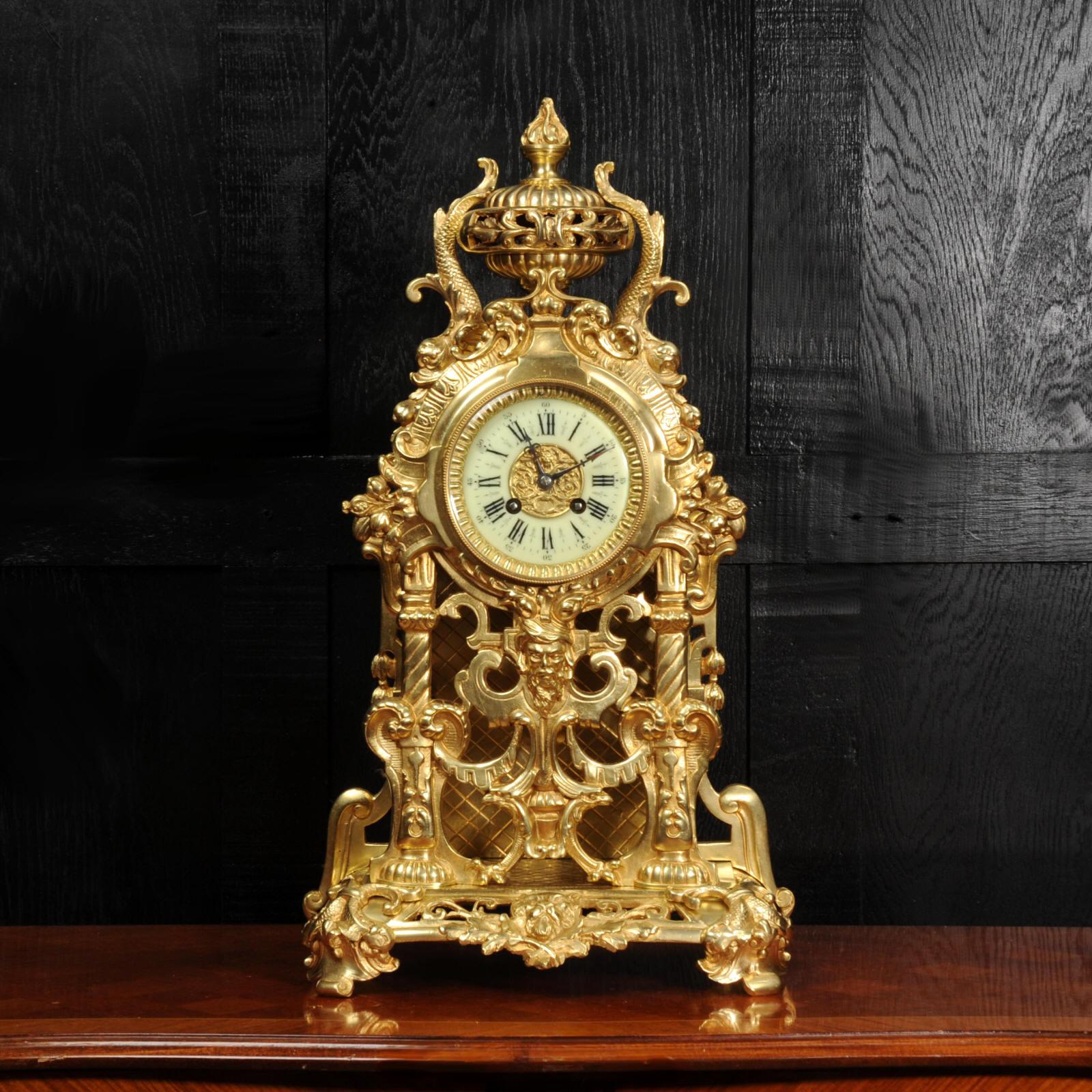 A large and superb antique French gilt bronze clock, circa 1880. It is beautifully modelled in the Baroque style, boldly formed of scrolling panels with grotesque masks, and dolphins. To the top is a large urn with a flaming finial and dolphins.
