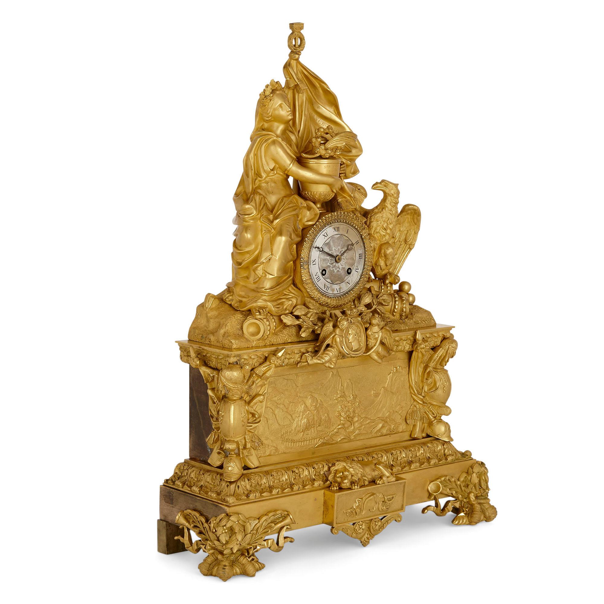 Große vergoldete Bronze-Kaminuhr zum Gedenken an Napoleon
Französisch, um 1840
Maße: Höhe 57cm, Breite 40cm, Tiefe 15cm

Die Kaminsimsuhr aus vergoldeter Bronze steht auf einem rechteckigen, gestuften Sockel mit vier Zierfüßen. Die untere Etage