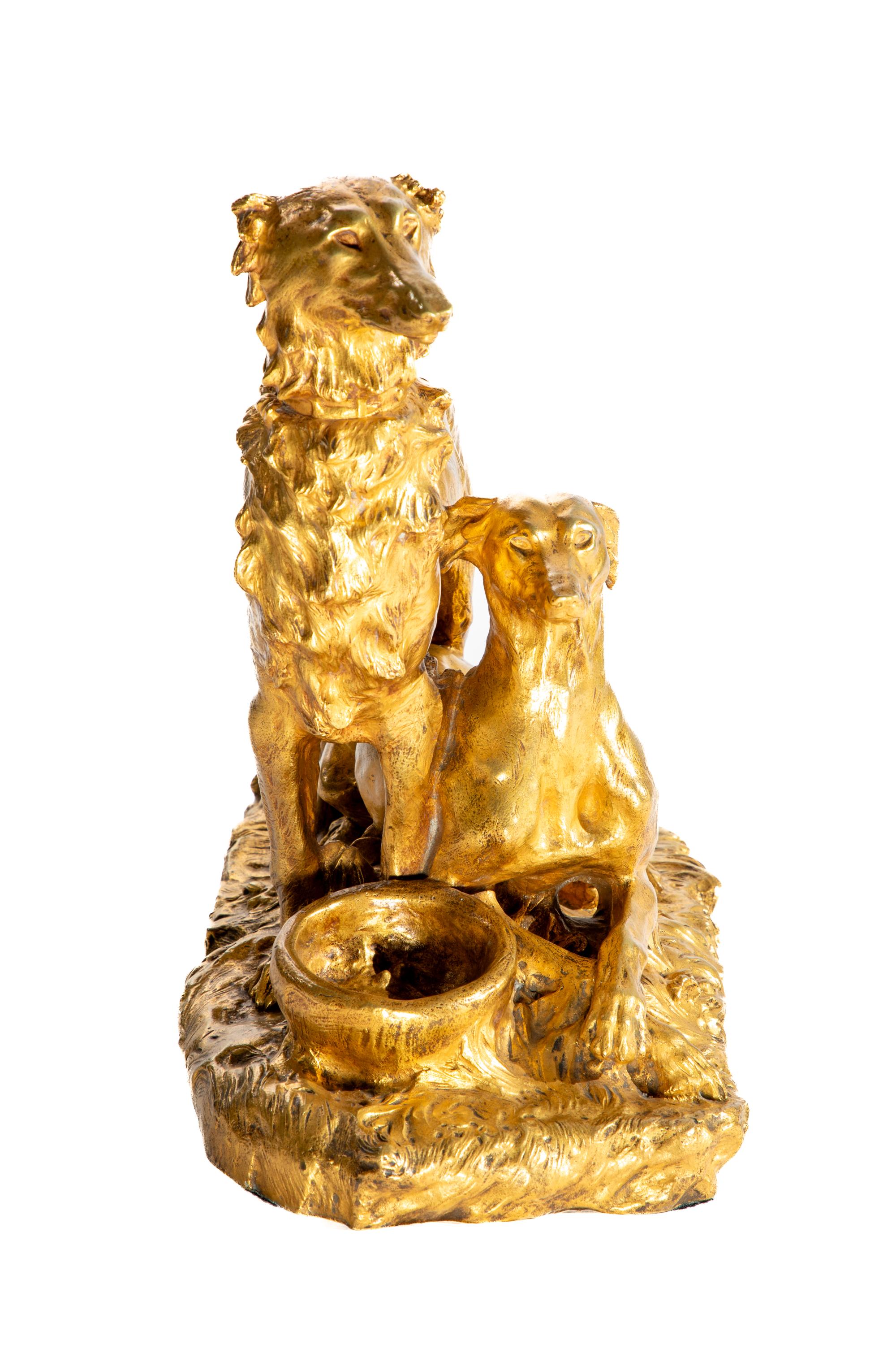 Scultura in bronzo dorato di due cani con un piatto.  Un cane in piedi, l'altro sdraiato.

Con dedica a Thomas Cartier / copyright 1904 di Georges Raingo