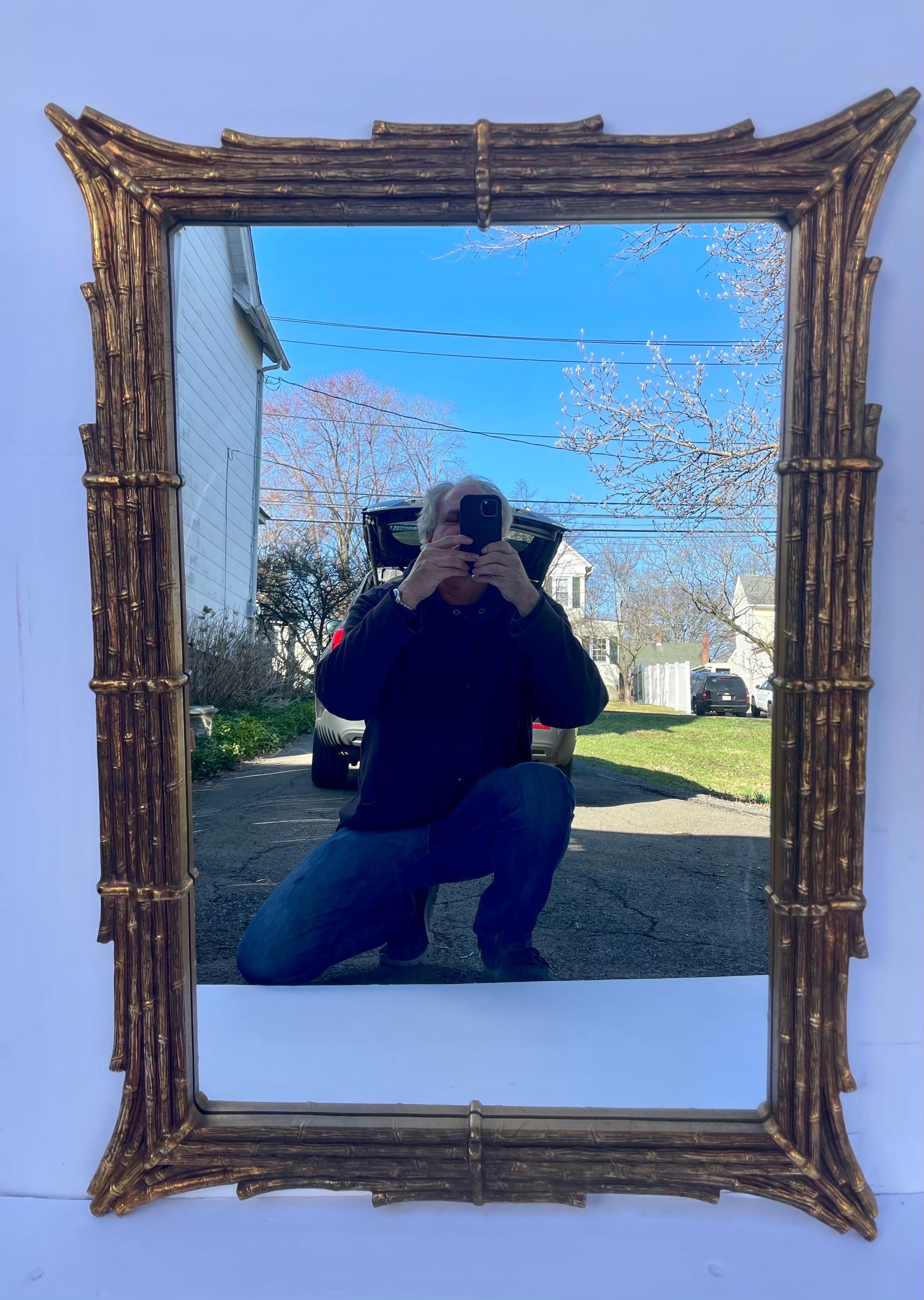 Large Scale Gilt Hollywood Regency Style Faux Bamboo Mirror Circa 1960's-1970s. Nicely shaped  wide stepped frame.   Wire on back for hanging, has hangers on back to hang horizontal as well.  Measures 31.5
