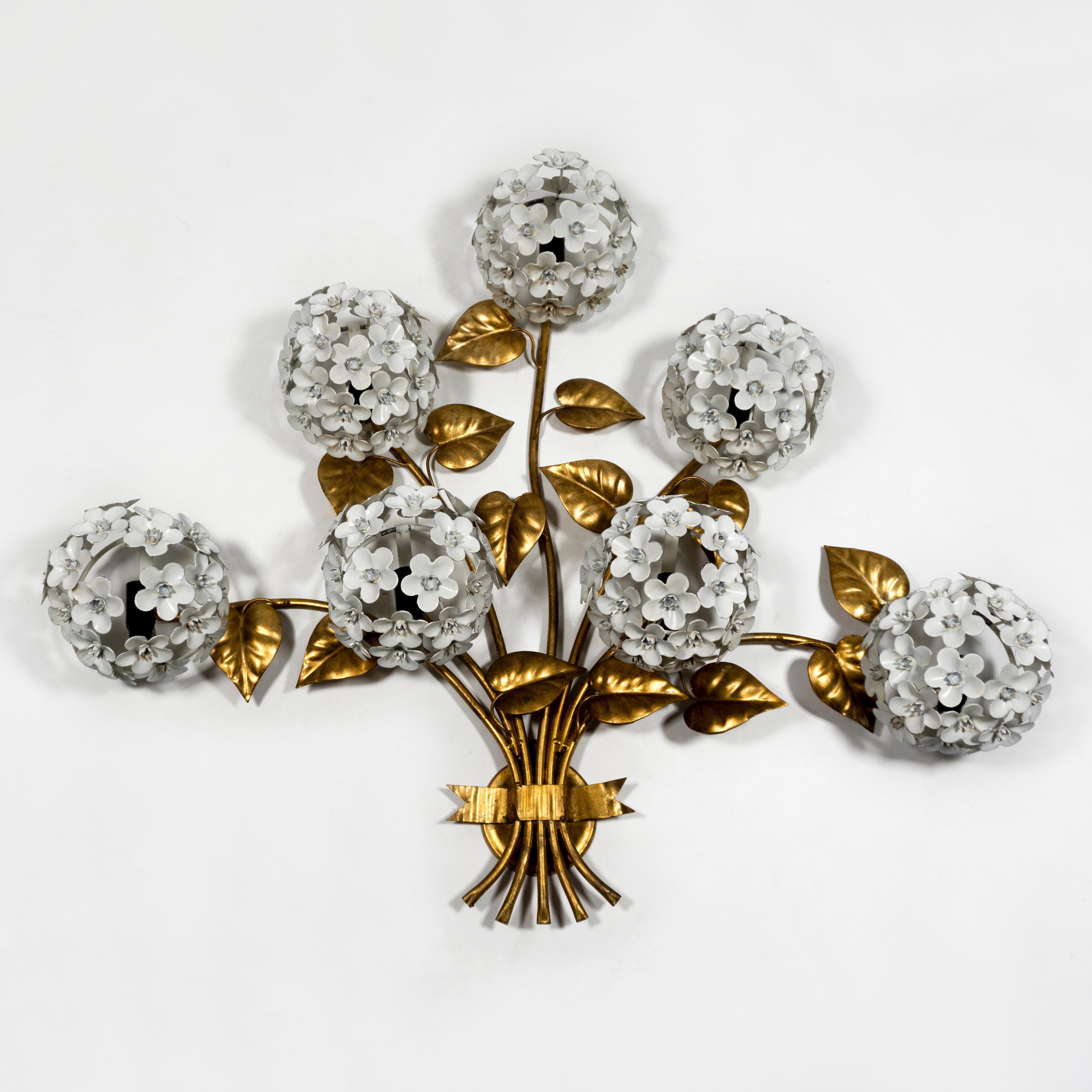 Une superbe, élégante et très glamour applique murale dorée avec des feuilles décoratives dorées et sept fleurs d'hortensia en émail blanc - avec une lumière derrière chaque fleur. 
Lorsqu'il est éclairé, ce luminaire présente un aspect magnifique