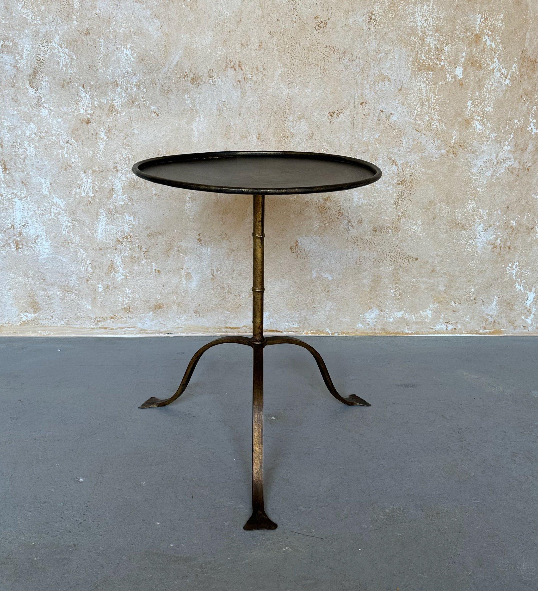 This large iron side or drinks table was recently crafted by European artisans using traditional iron working techniques. It features a hand applied gold finish with dark undertones and is mounted on a sturdy but fanciful flared tripod base. With