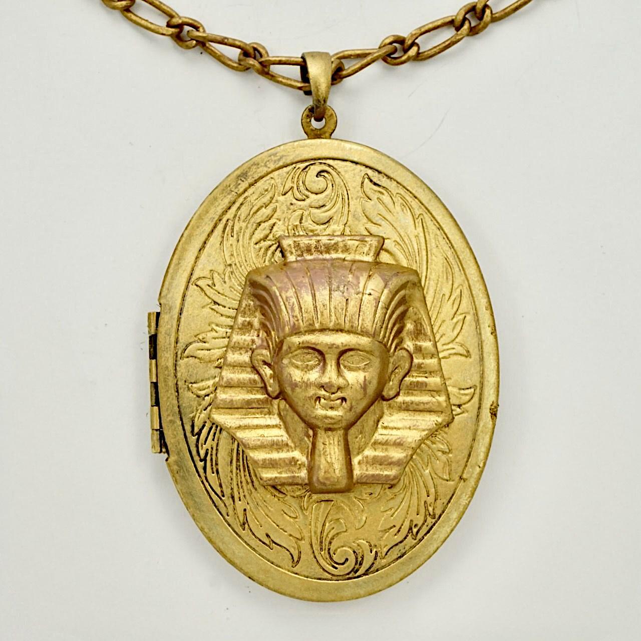 Großes Pharaonenmedaillon aus vergoldetem Metall mit Kette, innen auf einer Seite mit blauer Emaille versehen. Das Medaillon hat eine Länge von 6,4 cm und eine Breite von 4,7 cm. Das Scharnier funktioniert gut, und das Medaillon lässt sich gut