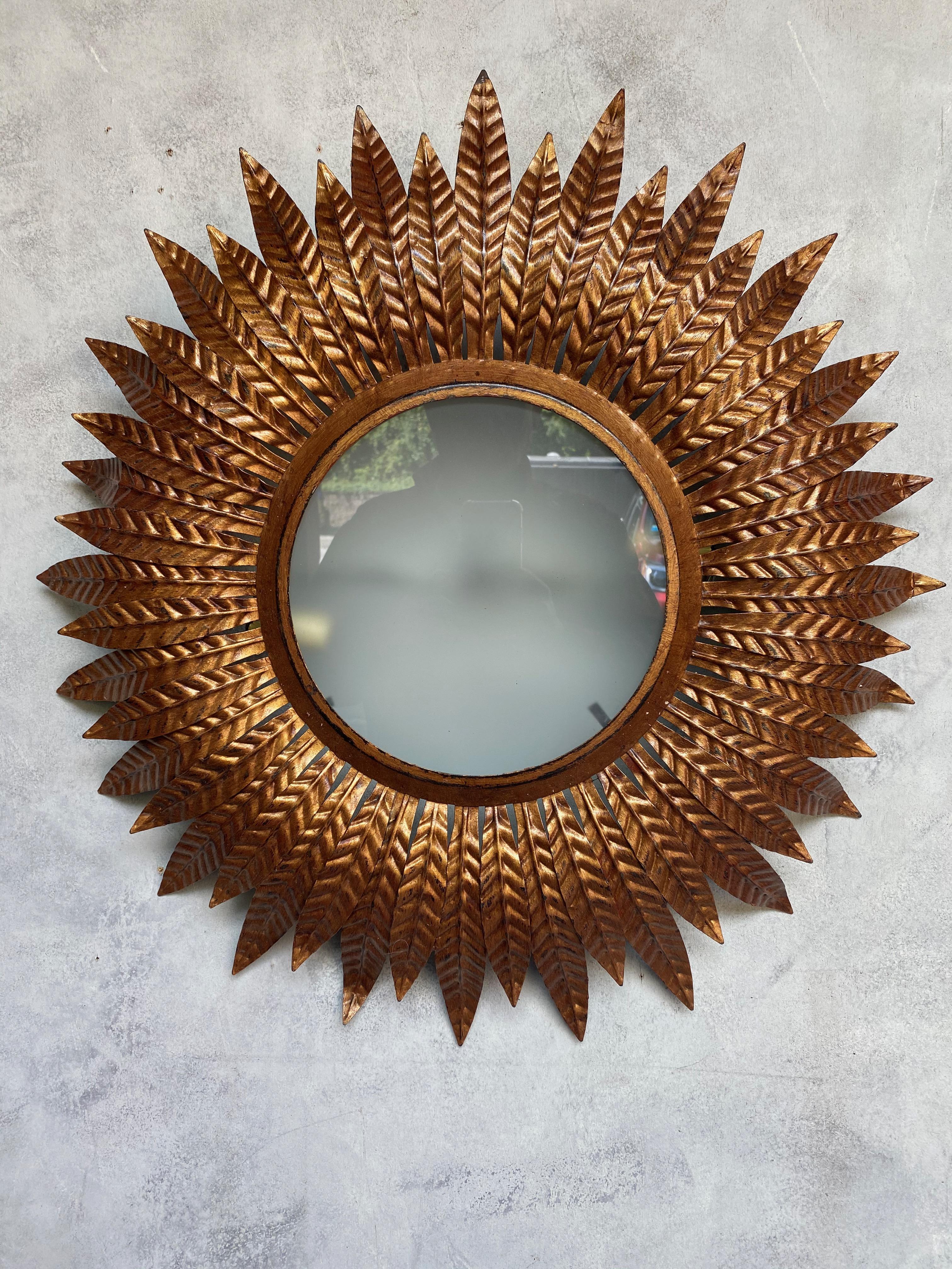 This is an interesting Spanish flushmount ceiling fixture from the 1950s. The gilt metal has a rich, deep antique gold patina. The sandblasted glass diffuser is surrounded by a double layer of closely arranged leaves, alternating between a longer