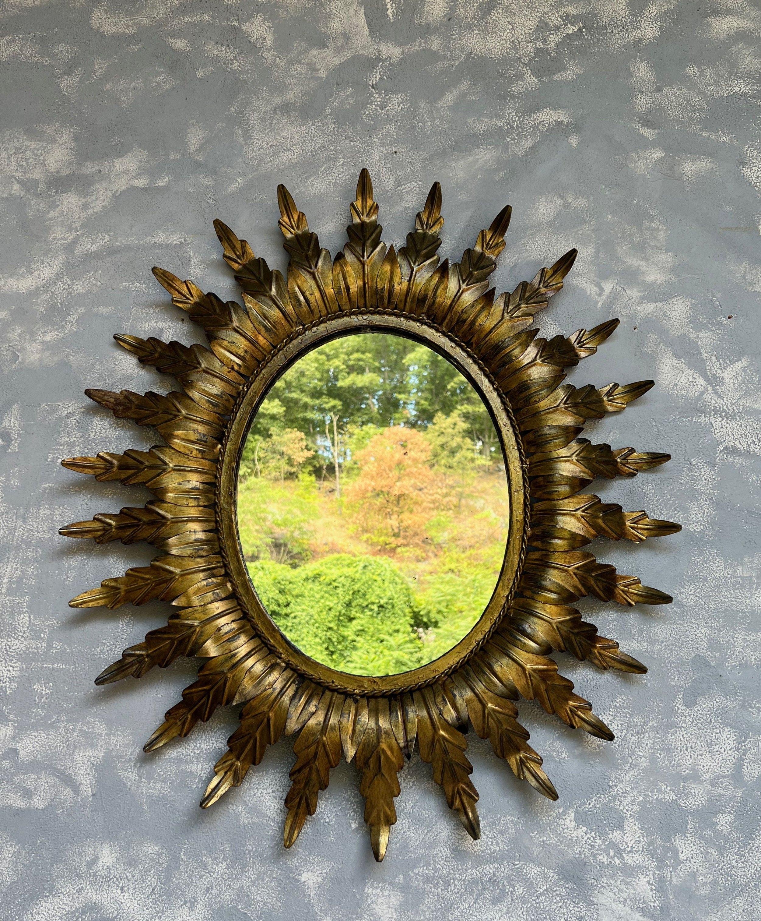 A large mid century oval sunburst mirror with radiating leaves surrounding a braided frame in a rich gilt patina. We recently added a felt backing to the mirror to give it more protection and a finished look. 

Spanish, 1950s. Very good vintage