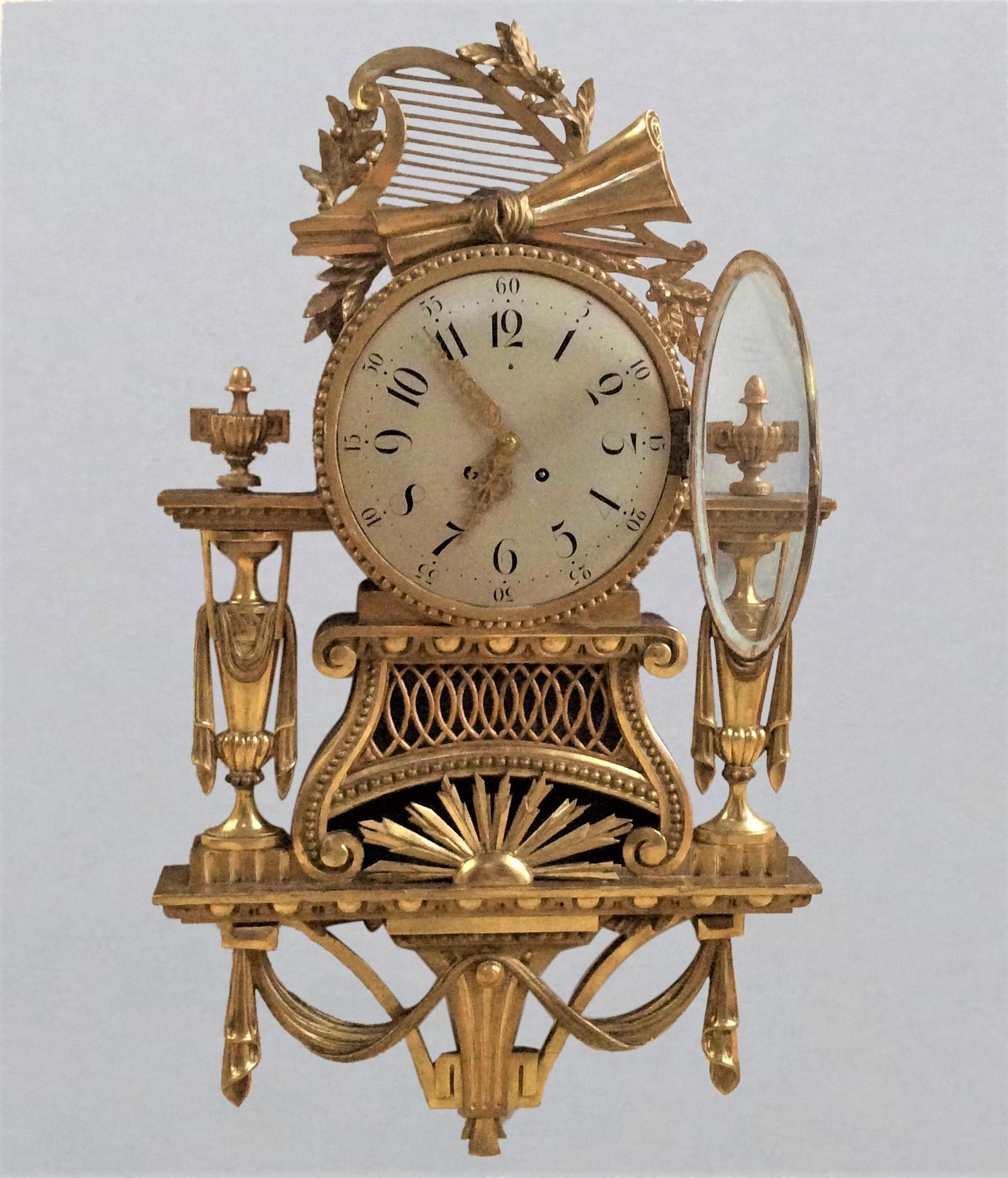 Gilt wood cartel clock.


Painted dial with Roman numerals and pierced gilt hands. 

 Giltwood case with swag decoration, turned finials, surmounted by a harp with starburst decoration below the dial.

Eight day movement by Gustav Becker with
