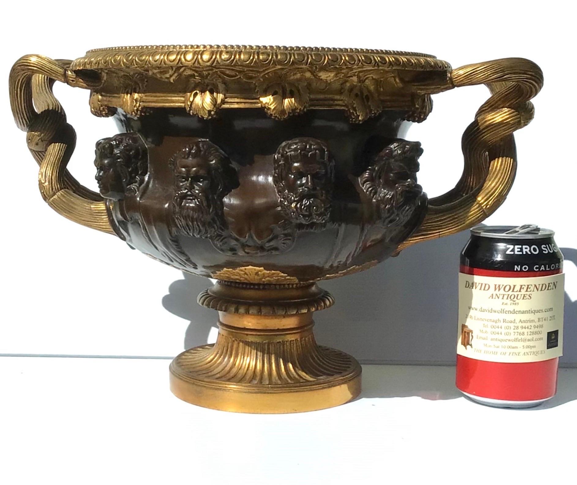 Fabulous large gilted bronze 'Warwick' vase by Barbedienne, Paris circa 1860, modelled after the original the masks between the entwined vine handles, egg and dart rim with grapevine decoration, on a round gilt bronze pedestal. 

Measures: 33cm x