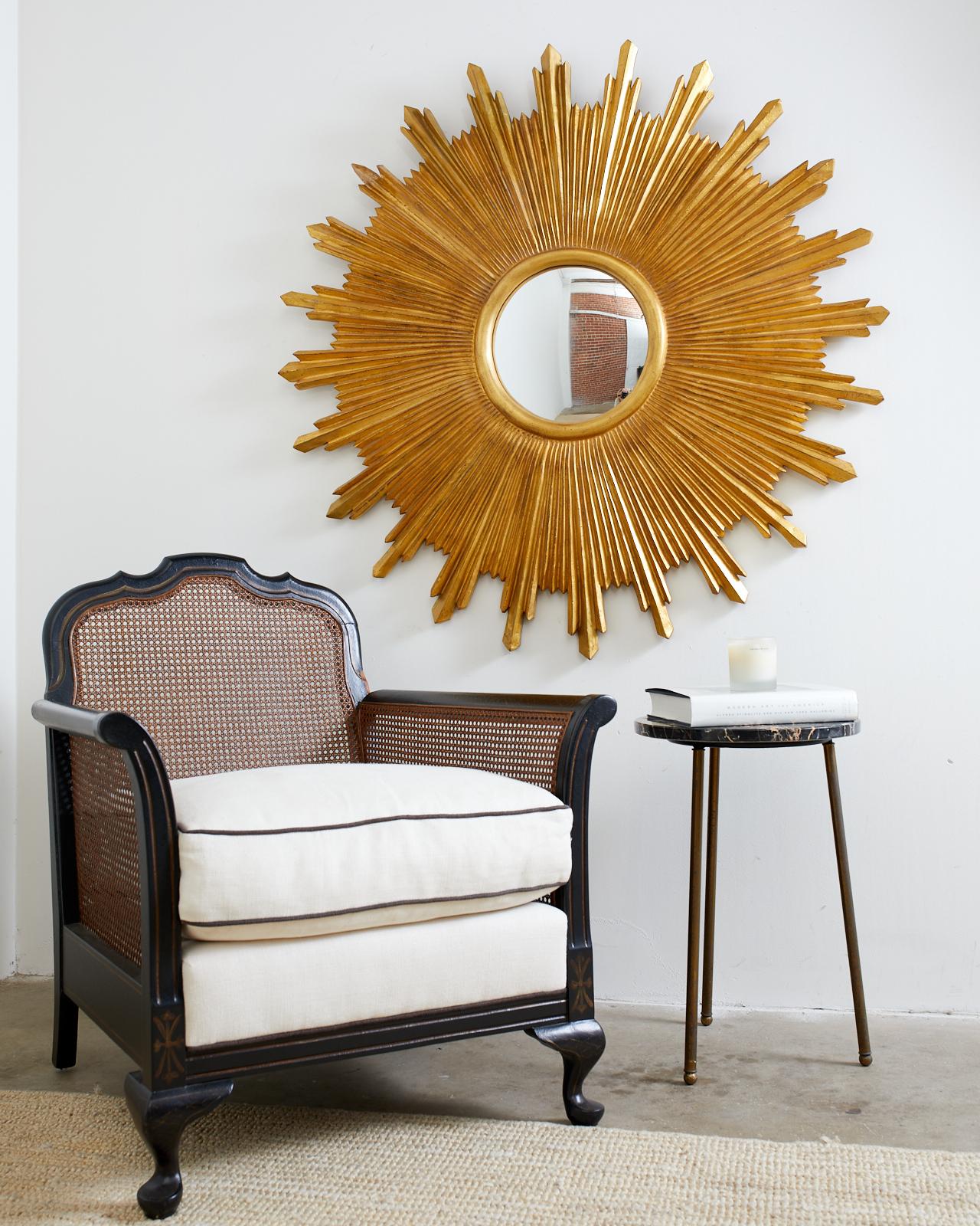 Grand miroir dramatique en bois doré, fait à la main, avec un verre convexe. Fabriqué par Carvers Guild, il présente un cadre sculpté avec des facettes angulaires recouvertes de feuilles d'or. D'un diamètre de plus d'un mètre, il attire l'attention