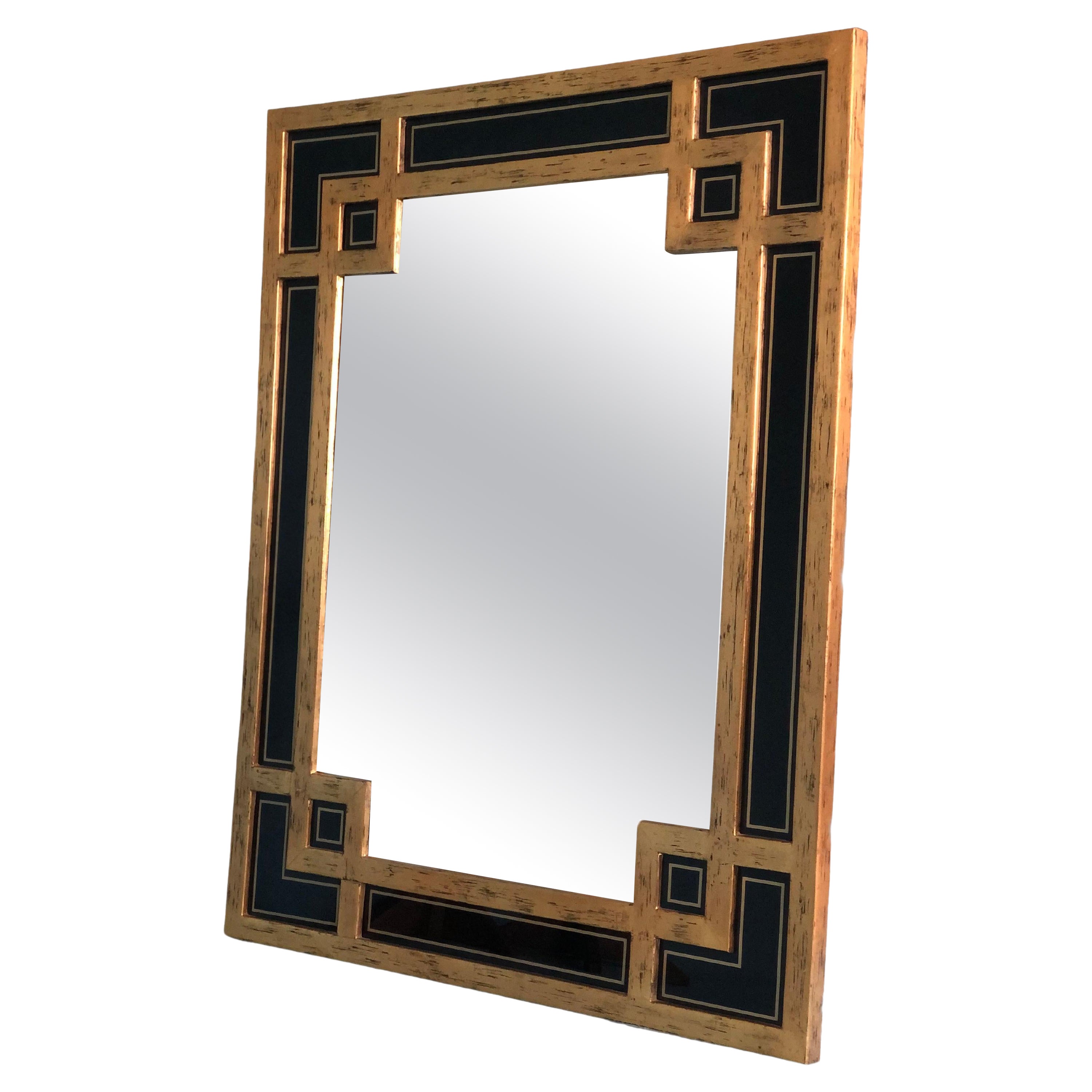 Ce grand miroir, fabriqué en Belgique par Deknudt dans les années 1970, présente un cadre en bois magnifiquement doré avec un motif complexe de méandres. Le design est rehaussé par des panneaux de verre noir insérés, qui ajoutent de la profondeur et