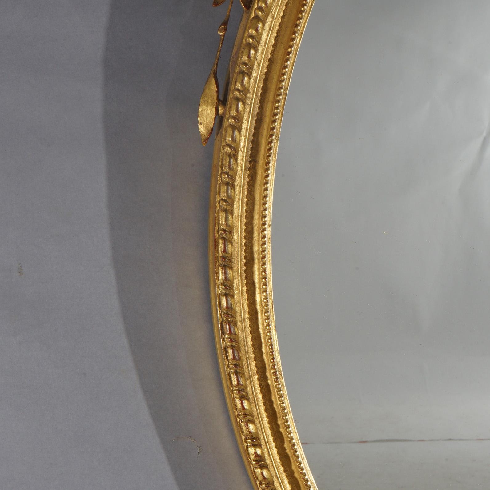 Specchio Grande specchio da parete ovale in legno dorato con elementi floreali, fogliame e volute del XX secolo in vendita