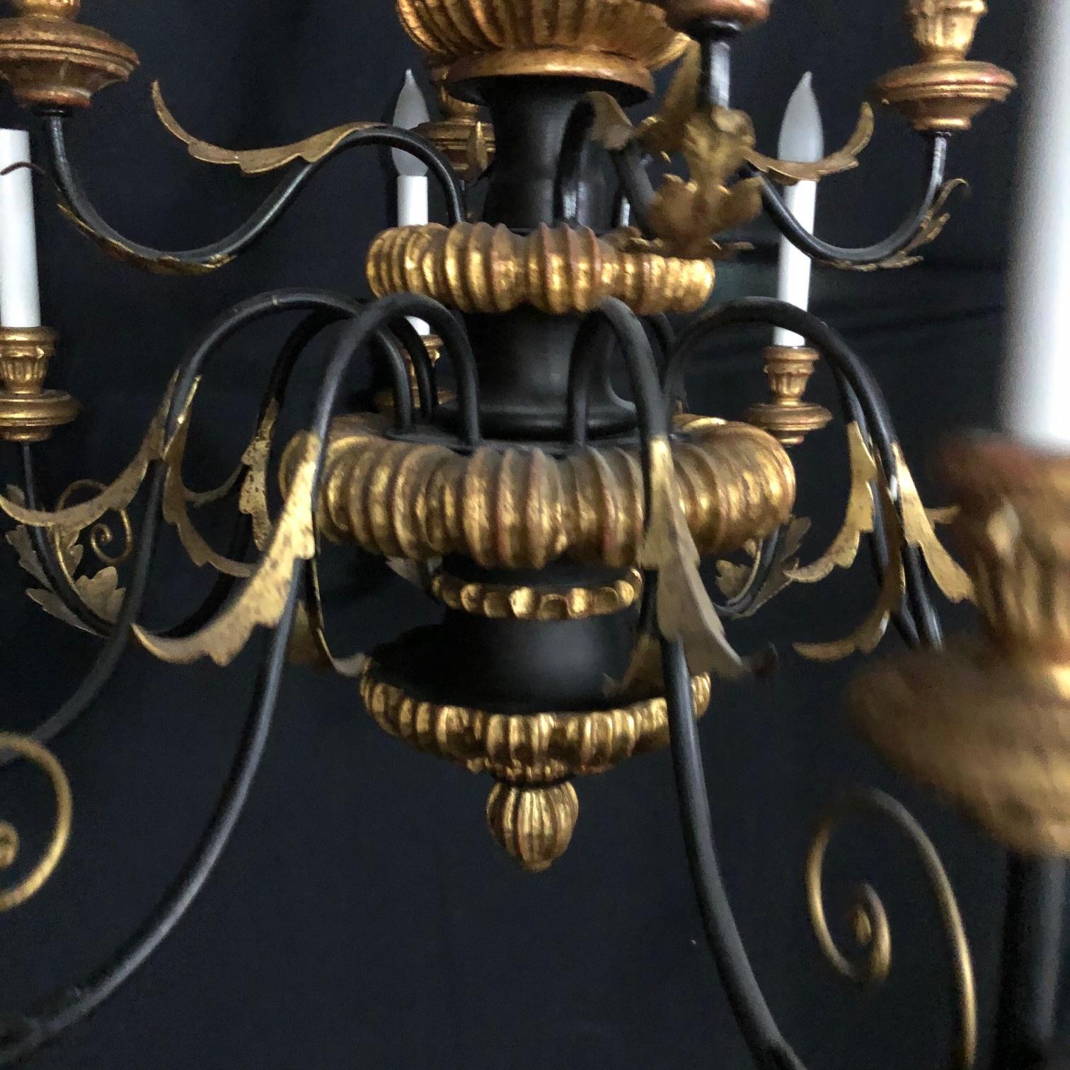 Large elaborate Rococo center shaft 12 arm Italian chandelier with two tiers: Lower tier has eight arms and upper tier has four arms. Garlands of golden acanthus leaves adorn the arms. The chandelier has a wonderful Regency style gold and black