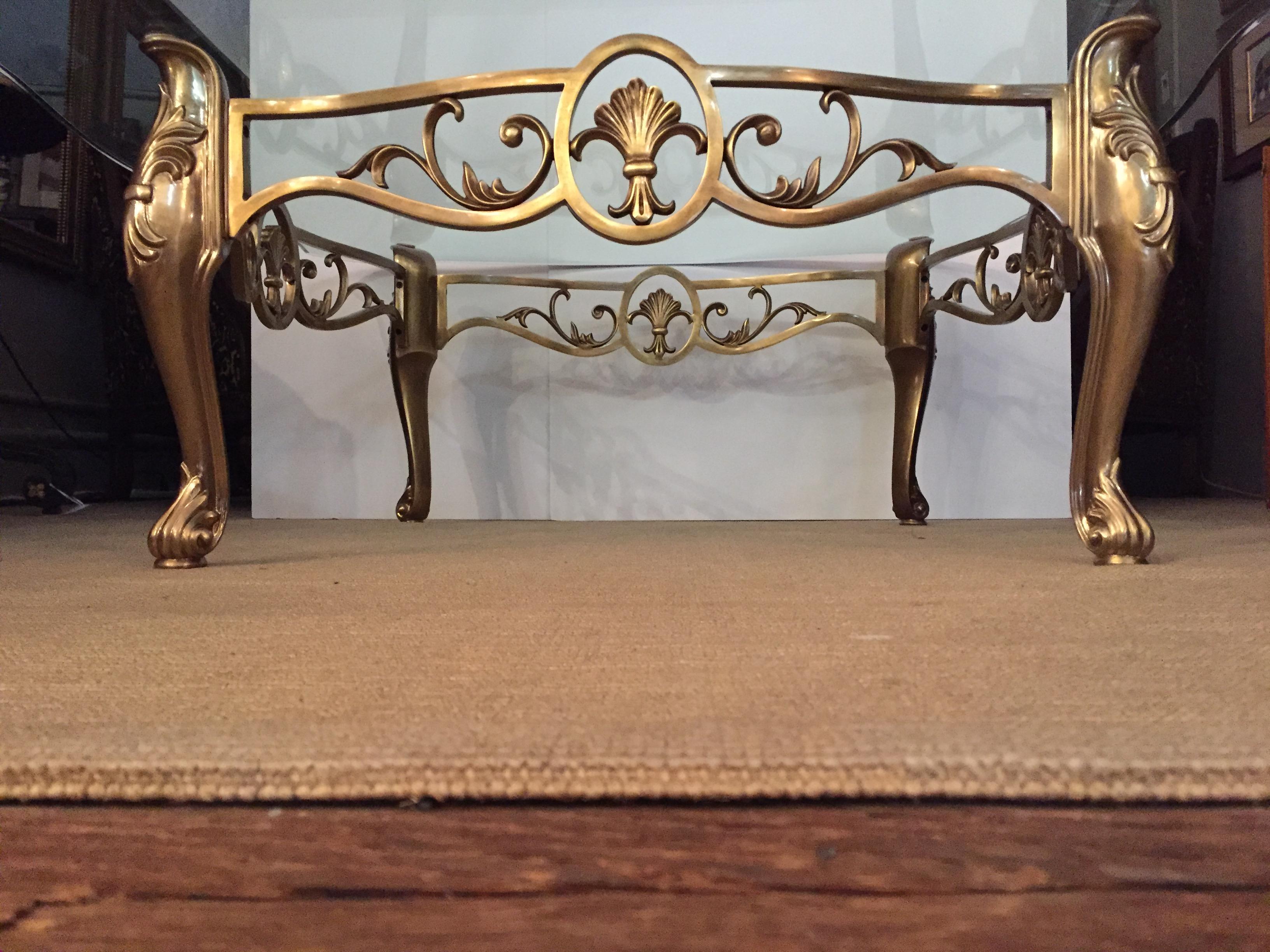 Beautiful Labarge almost square large coffee table having a scalloped heavy glass surface and satin brass base with shell and fleur di lis style decoration as well as cabriole shaped legs.