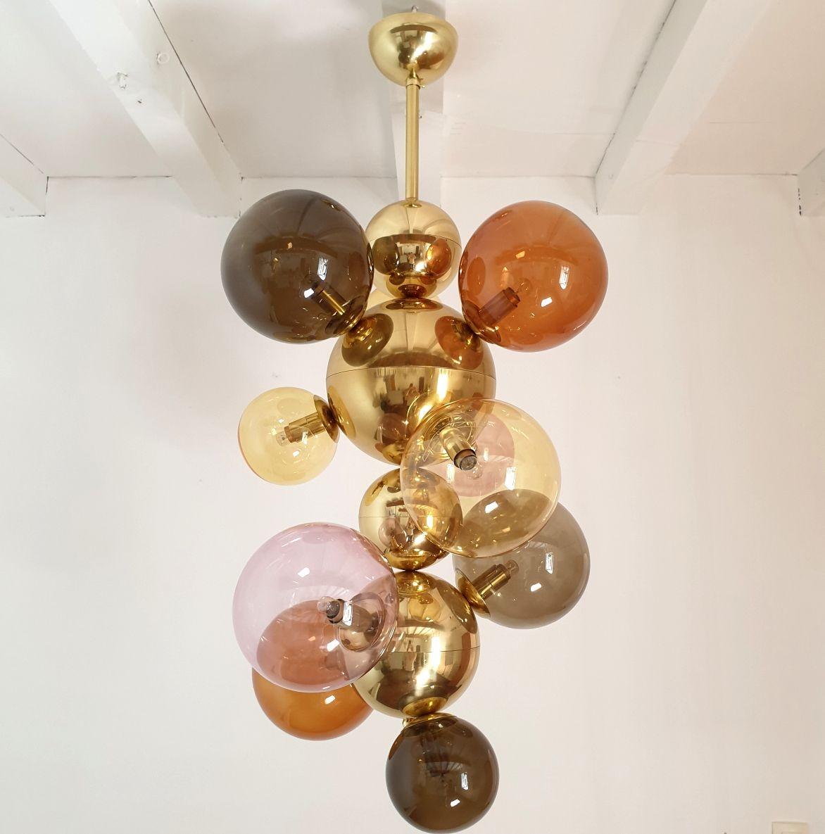 Large Mid Century Modern glass balls and brass chandelier or pendant light, Italy circa 2000s.
Two chandeliers available - A pair available.
Sold and priced individually.
The chandelier is made of two sizes glass balls, polished brass balls and