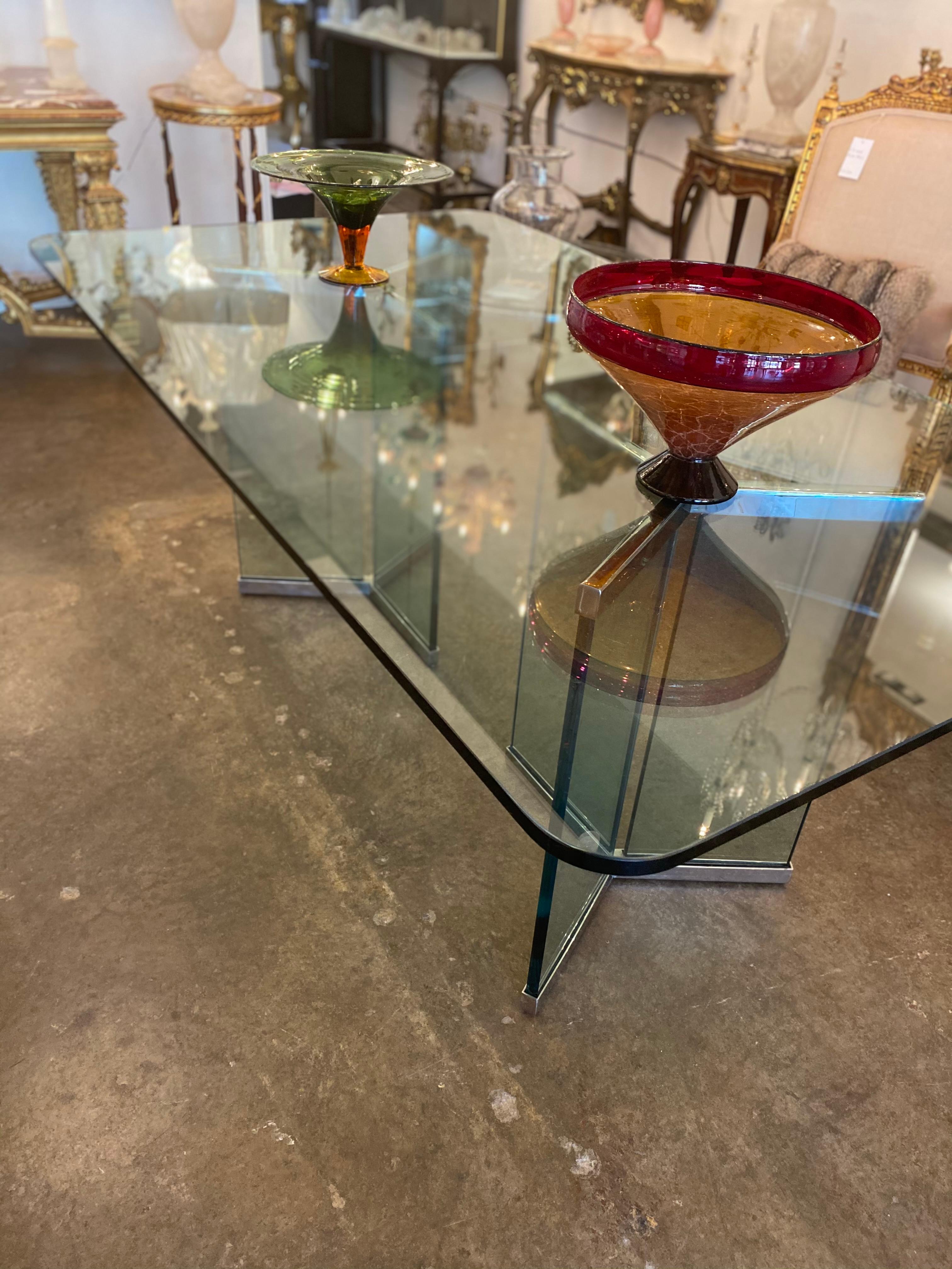 Large glass dining table with X-shape legs with a trim of silver plated on the bottom of the legs. Beautiful modern table.