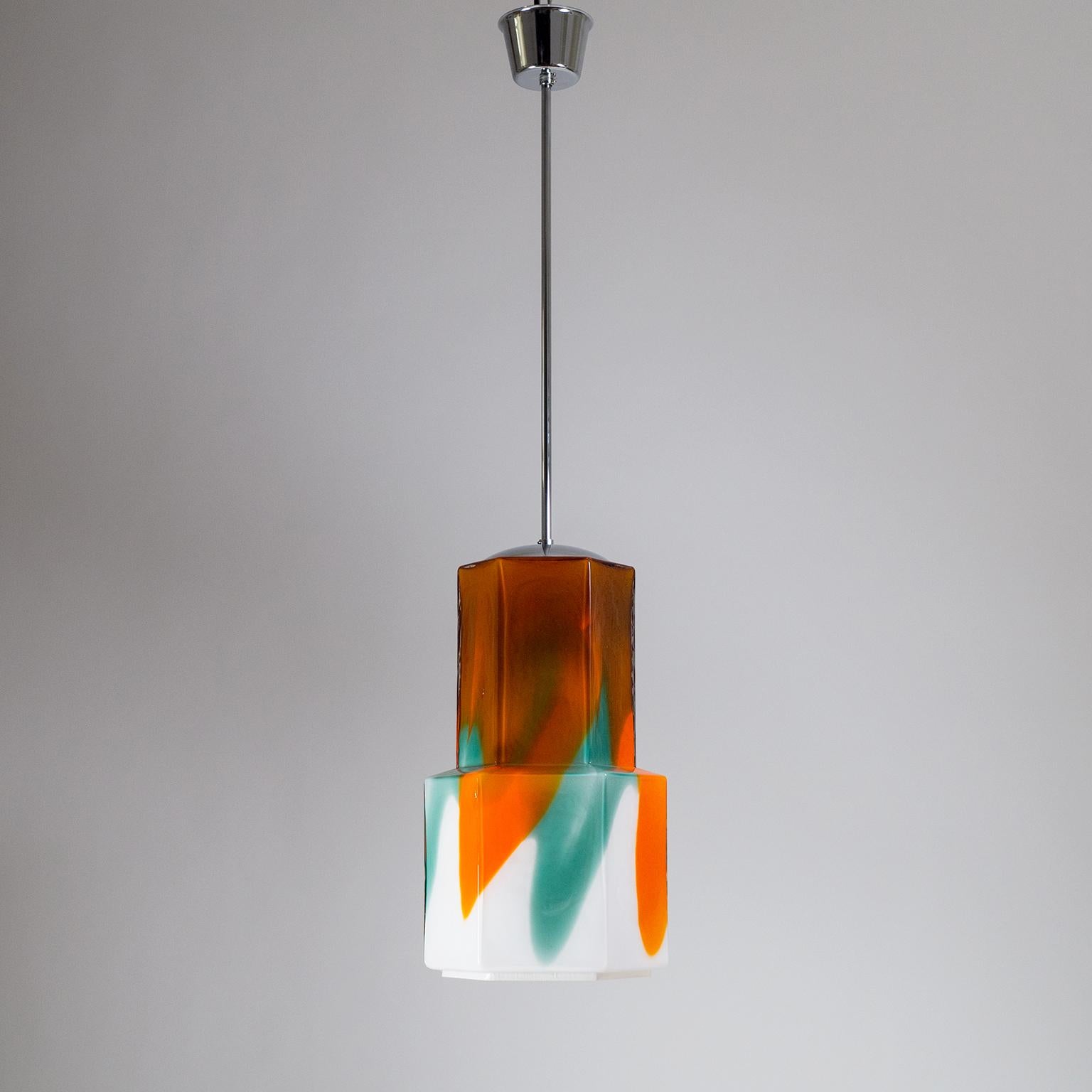 Bold glass pendant designed by Helena Tynell for Flygsfors, Sweden, 1960s. A large tiered hexagonal white glass diffuser with bold painterly streaks of orange and green and an organically textured surface. Chromed hardware with one E27 socket with