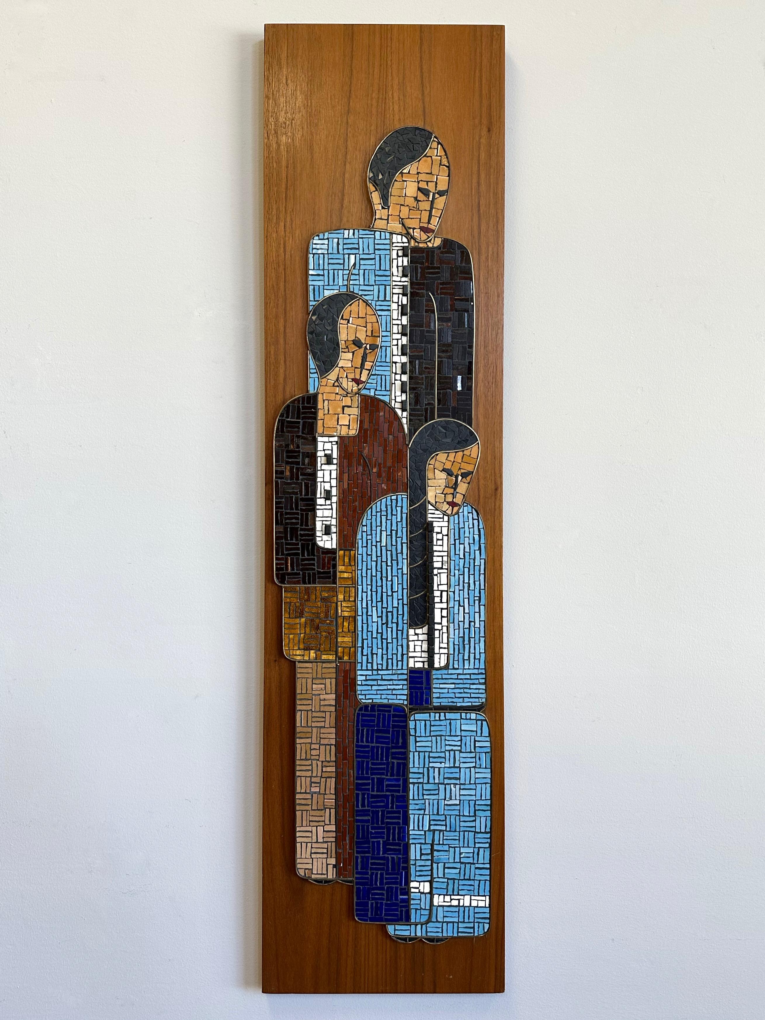 A large and exceptionally well done Mid-Century Modern glass and glazed ceramic tile mosaic on walnut board depicting a Native American trio, titled “Family”.

Stylized figures of a man, woman, and girl crafted of thousands of meticulously cut and