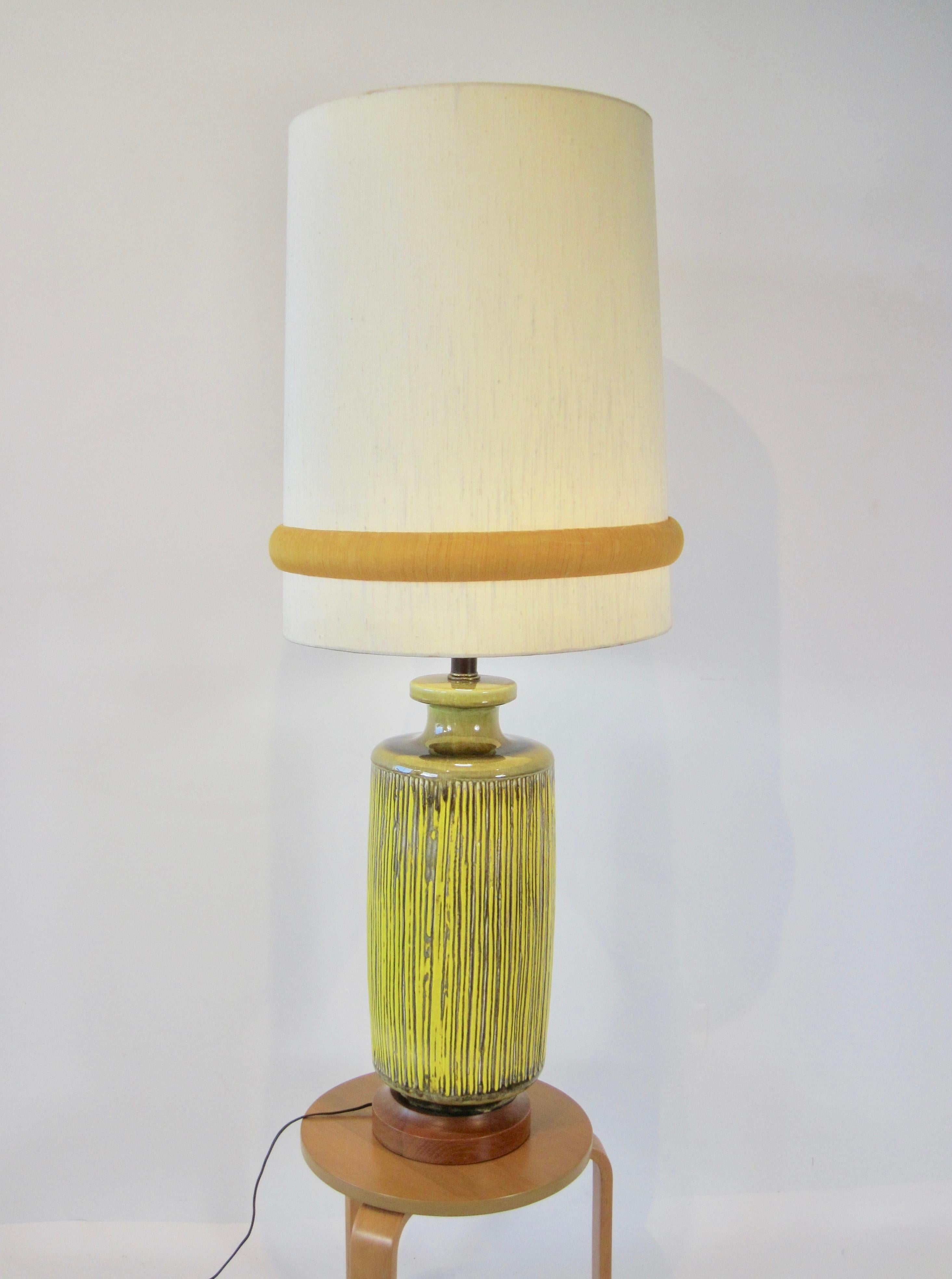 Reed style ceramic bottle neck lamp in yellow and olive green with wood base, and monumental shade. 
Can be purchased without shade, lamp measurements are 9