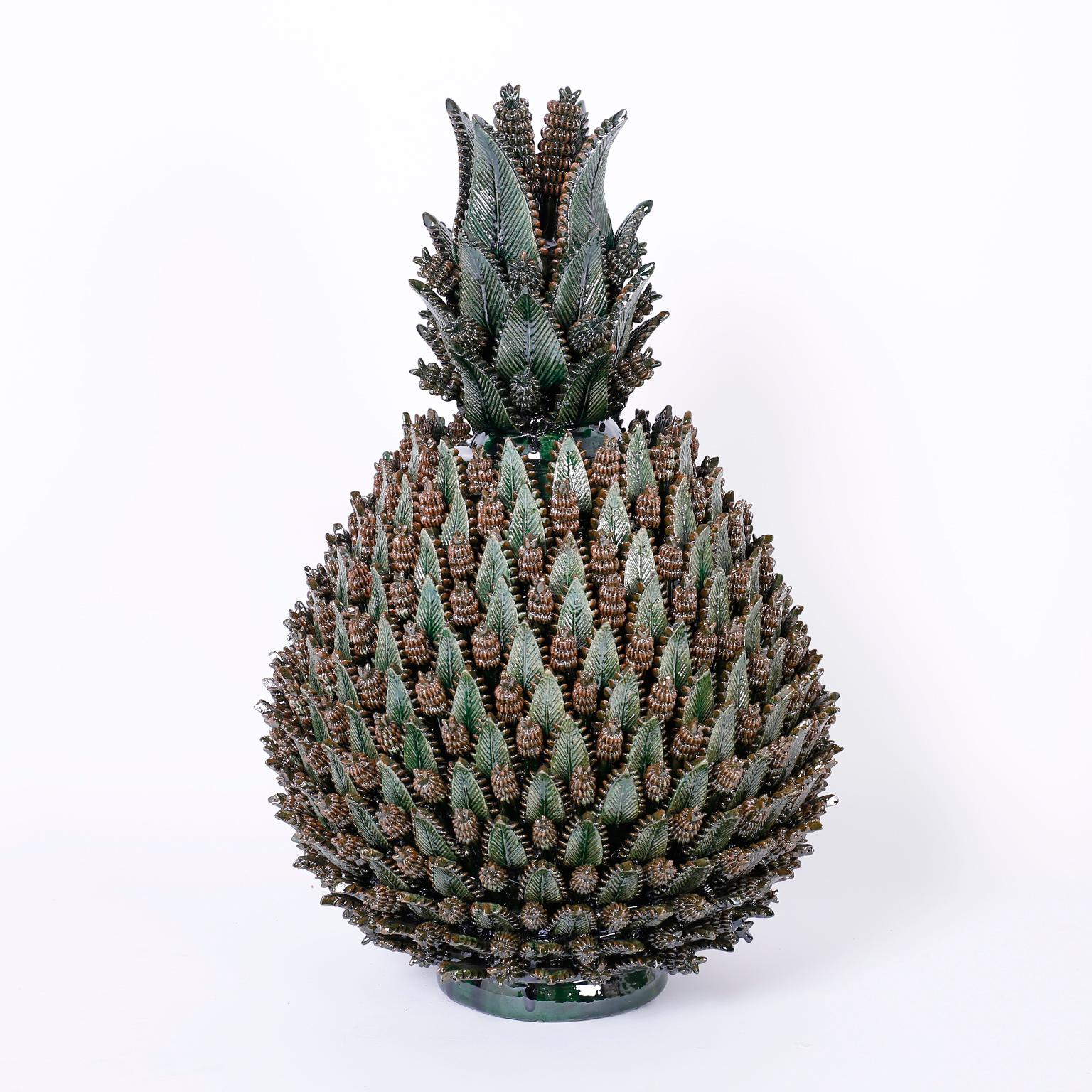 Here we have an amazing display of pottery brilliance in the form of this pair of glazed terra cotta stylized pineapples with an ambitious composition of leaves and cones in a varigated green glaze. One of a kind custom designed for F. S. Henemader.