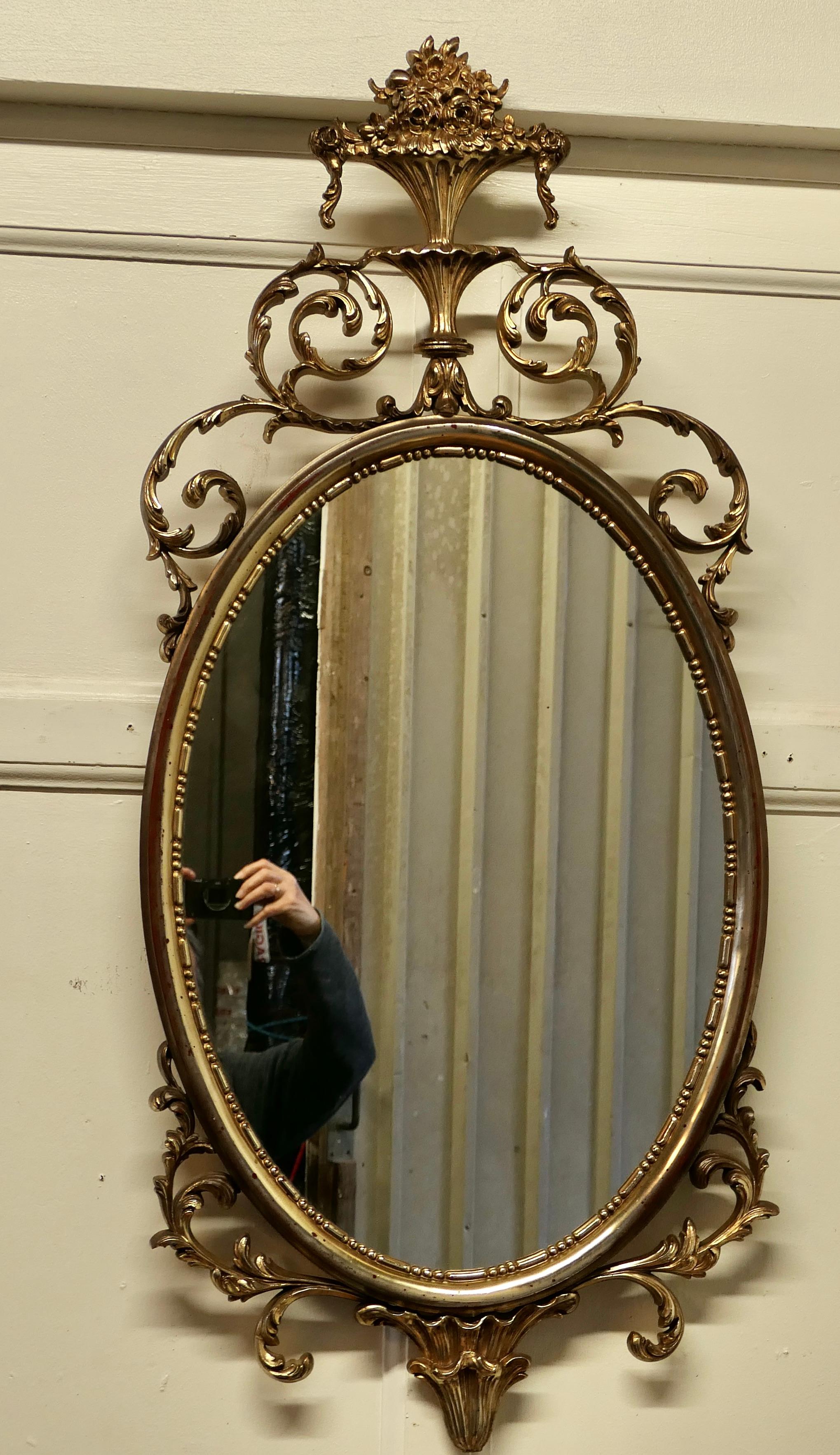 Large Gold Crested Rococo Style Oval Wall Mirror 

This impressive piece has a large decorative pressed frame which copies the distressed and slightly faded appearance of a much older piece
The artificially darkened gold finish showing red beneath