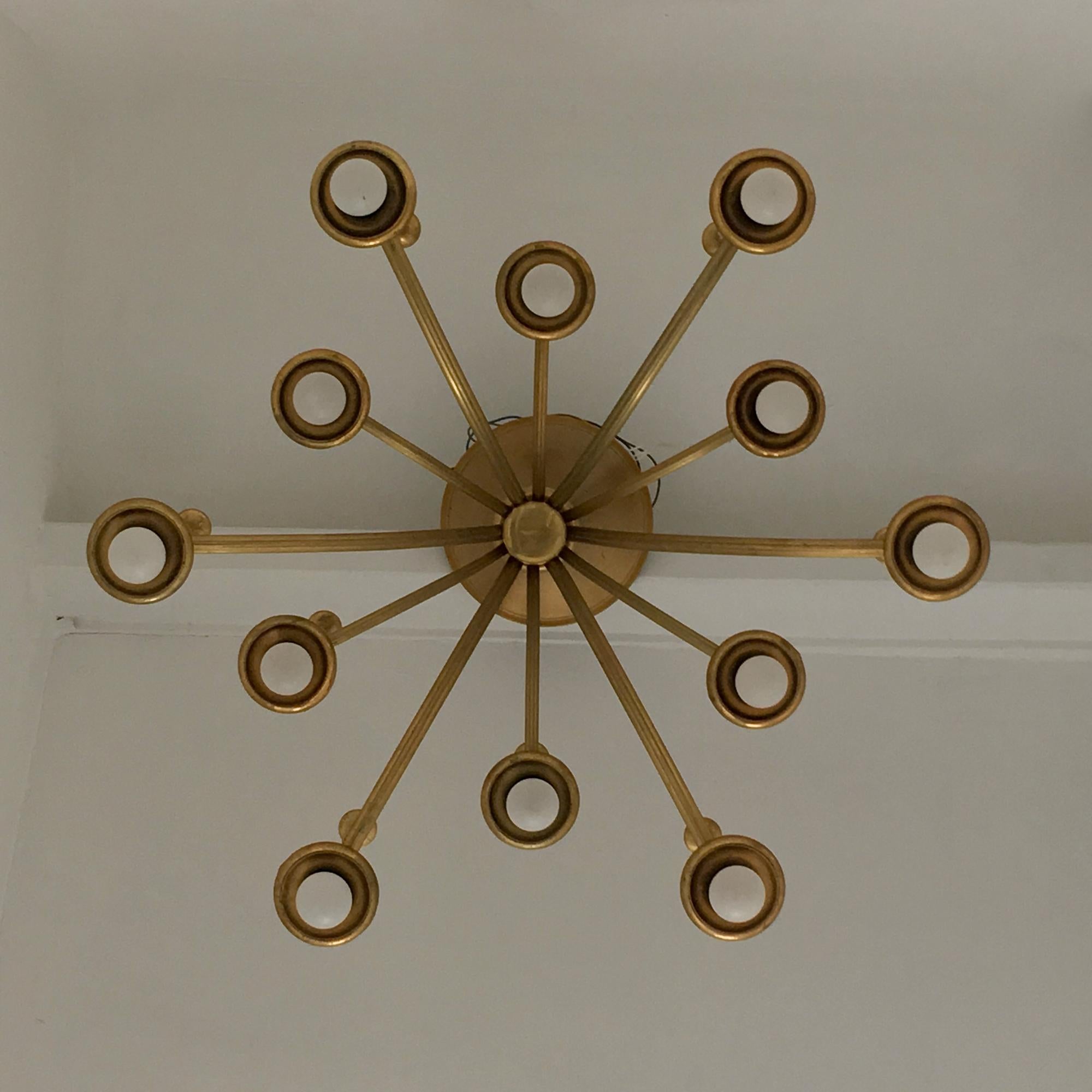 Unusual chandelier with gold satin lacquer finish; twelve arms in two tiers, each ending in an inverted trumpet and decorative stems, Italy, 1960s. 

The fixture is in fair vintage condition, with wear to the lacquer throughout in line with age. In