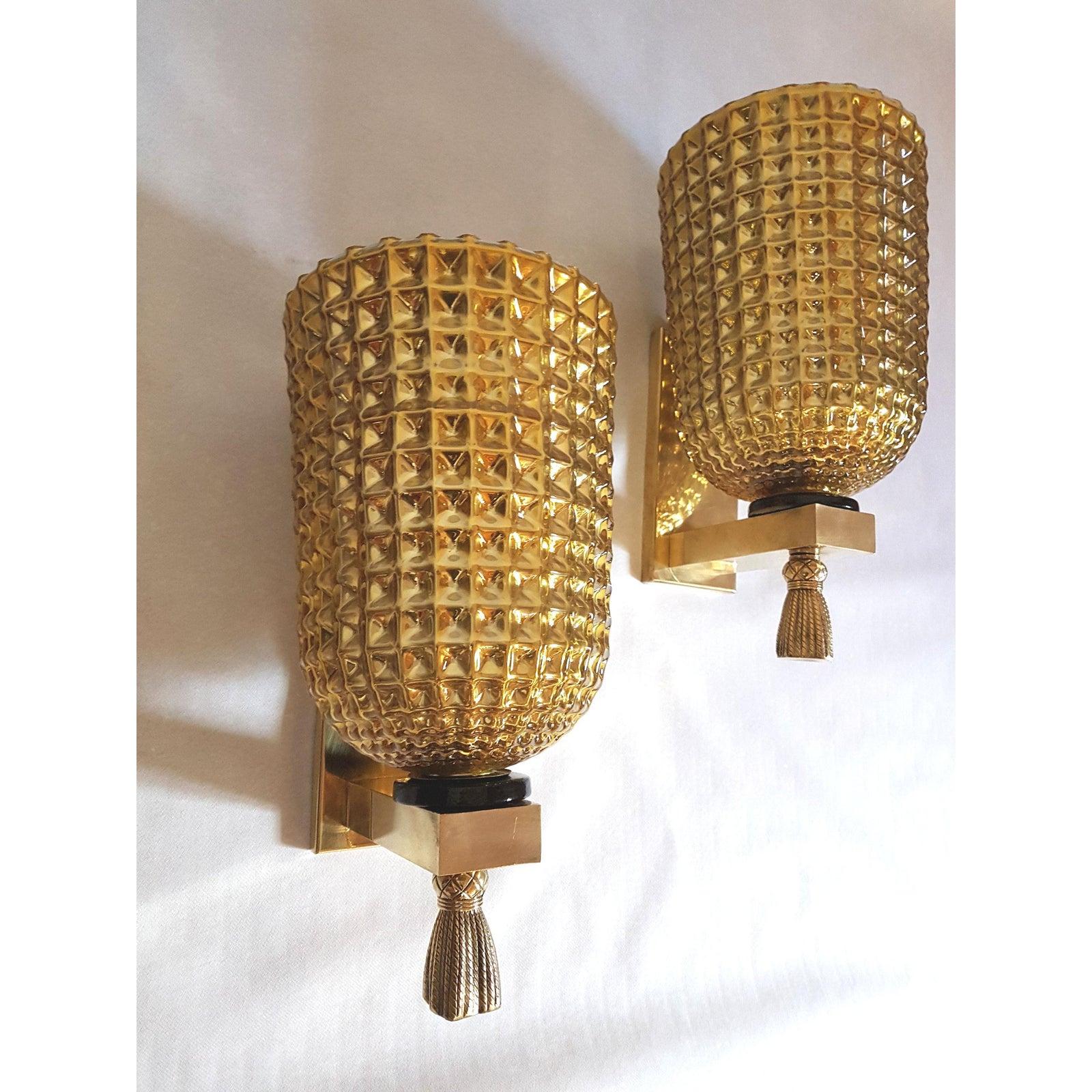 Pair of gold mirrored Mid-Century Modern Murano glass wall sconces, with brass mounts and bronze finials, attributed to Mazzega, Italy circa 1960s.
The mirrored Murano glass has a diamond pattern and is silvered inside.
The vintage sconces have