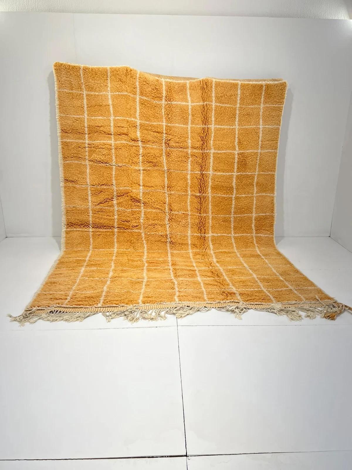 This large, neutral handwoven Moroccan rug was made by hand by skilled artisans in the Atlas Mountains. This handmade Moroccan rug is made from a high quality, richly colored warm golden orange brown wool base with a cream tattersall or grid