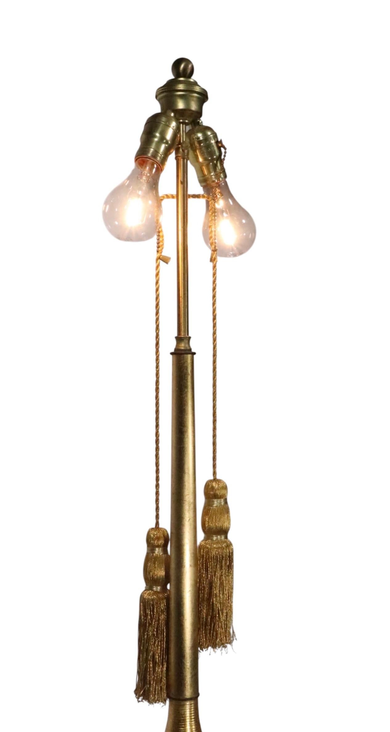 Chic gold toned Hollywood Regency style oversized table lamp. The lamp features features a bulbous form base with a ribbed surface finished in reflective metallic gold finish. Included is the original reflective gold tone drum shade. The lamp is in