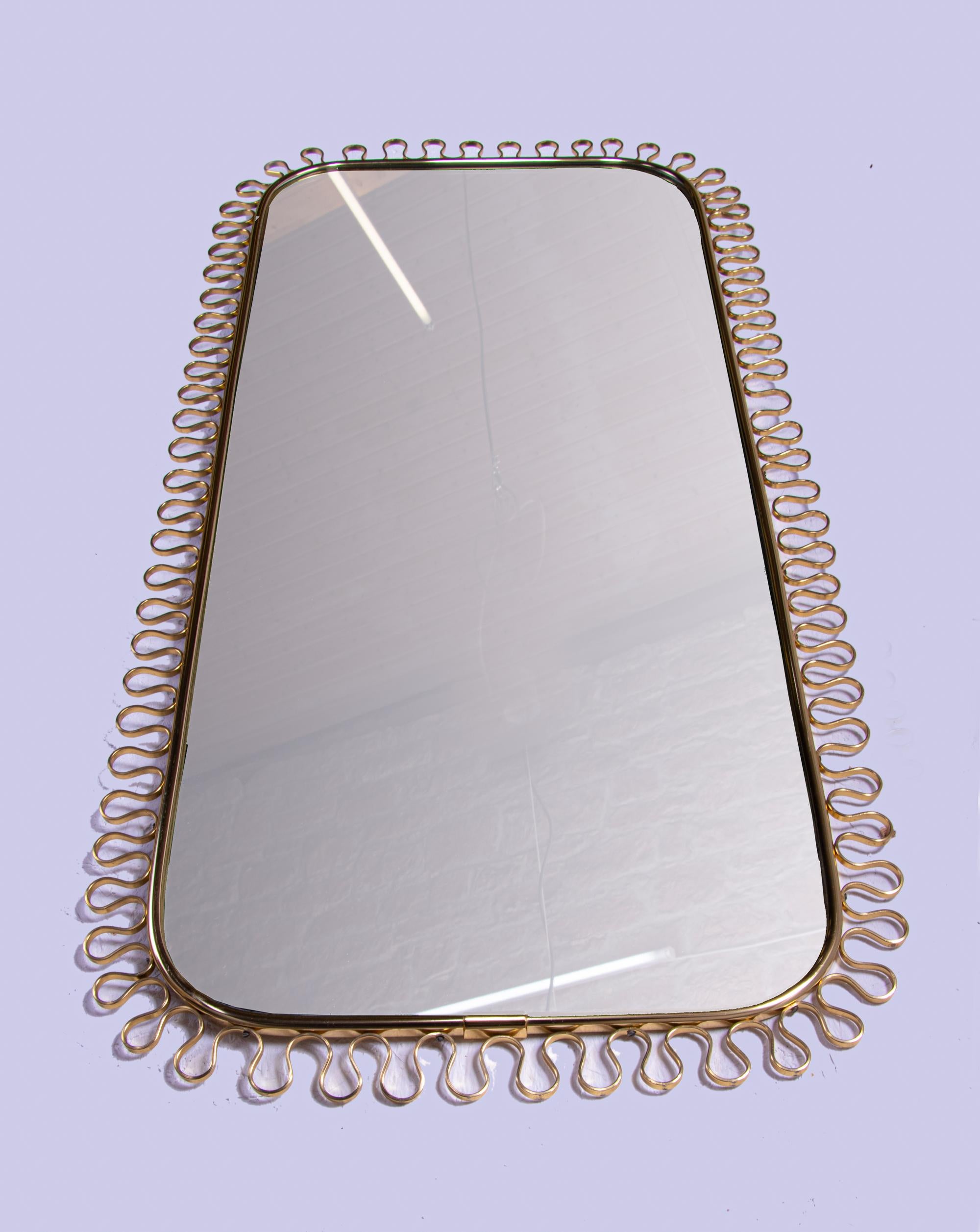 Elegant grand miroir mural du milieu du siècle avec verre miroir d'origine, encadré de nœuds en laiton doré sur un panneau arrière en bois massif avec la corde dorée d'origine. Conçu par Josef Frank pour Svenskt Tenn, Suède, vers 1950. 
 
Dimensions