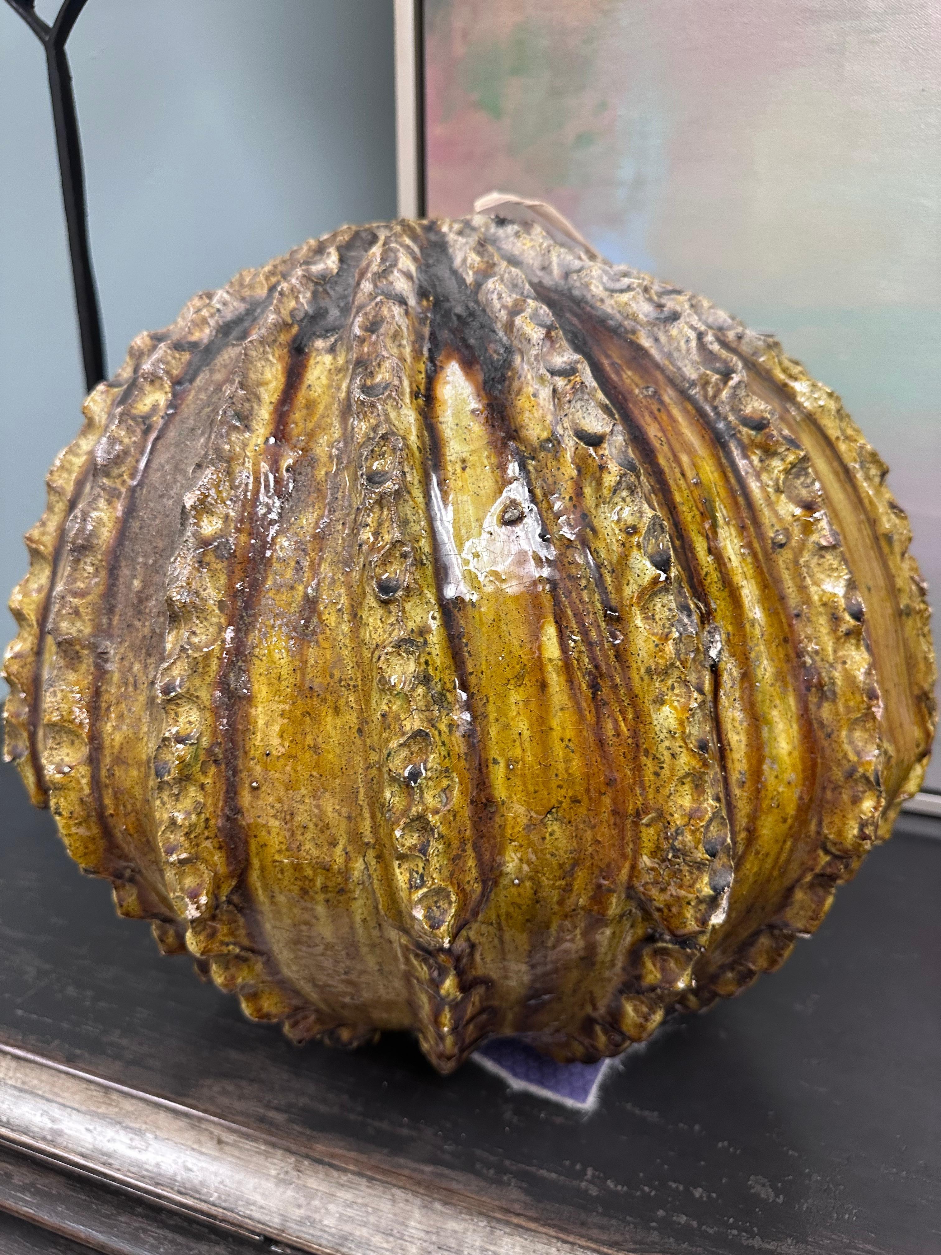Questo grande oggetto scultoreo in ceramica dalla forma organica che ricorda un cactus o una zucca è un bellissimo oggetto d'arredamento. Il pezzo è sferico con pronunciate creste verticali irregolarmente smerlate, che gli conferiscono una
