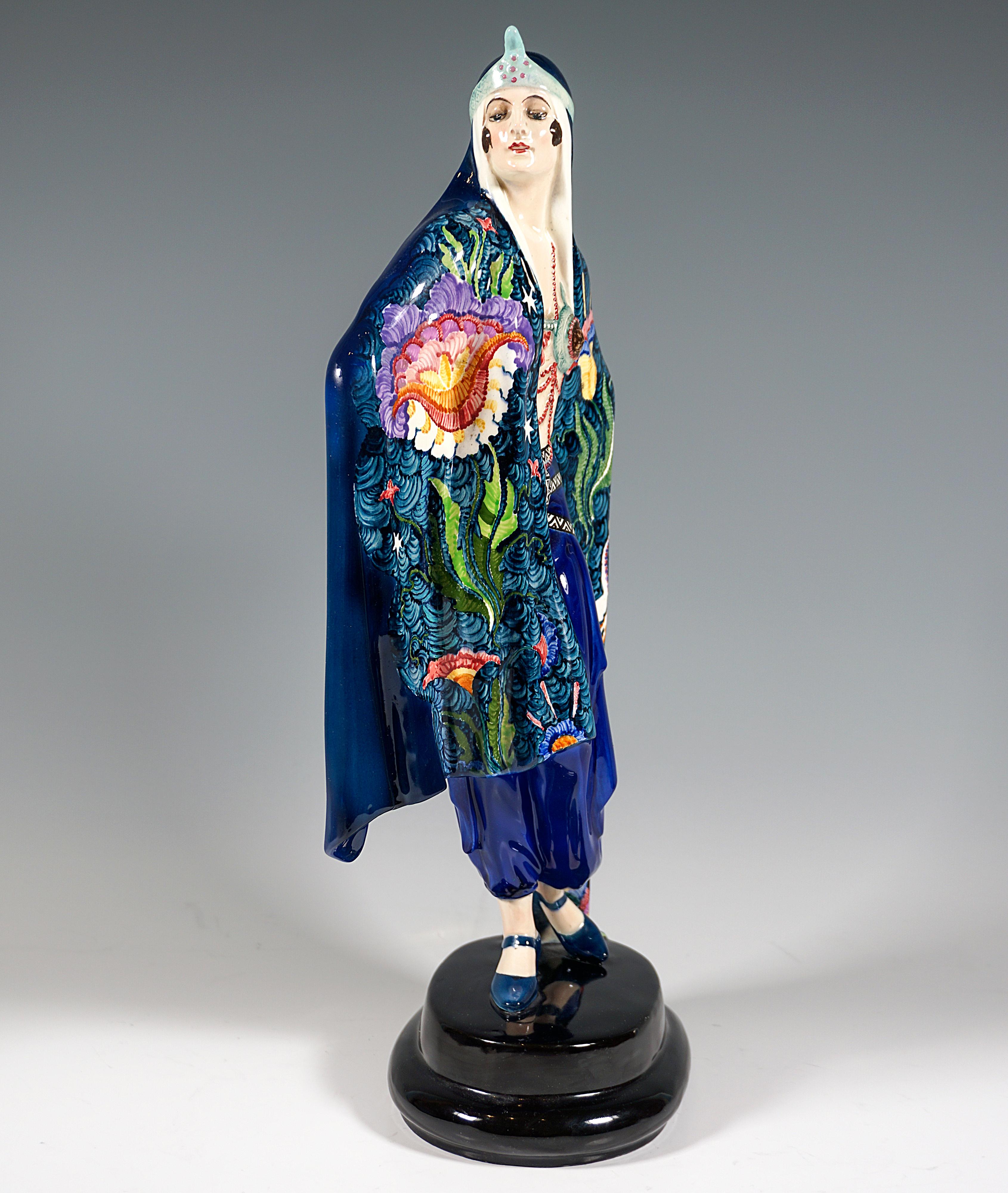 Sehr außergewöhnliche dekorierte Goldscheider Art Deco Keramikfigur aus den 1920er Jahren:
Darstellung einer stehenden, stolz zur Seite blickenden Dame in orientalischem Gewand, eingehüllt in ein großes, bis zum Boden reichendes blaugrünes Tuch, das