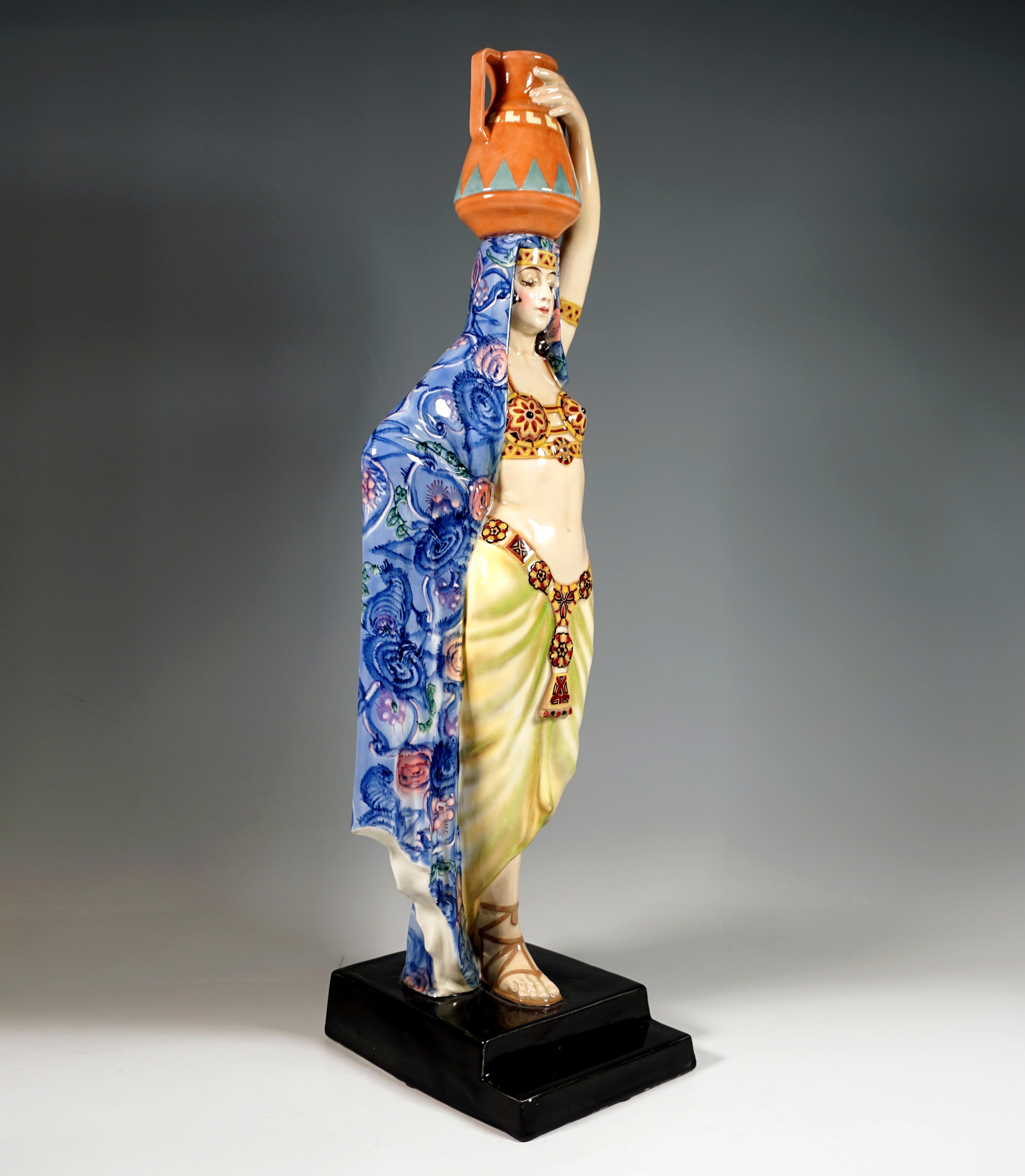 Very large and rare Goldscheider ceramic figurine of the 1920's: 
Striding graceful young lady in oriental clothing, balancing an amphora on her head, the delicate bustier, essentially consisting of two decorated cups and held together by ribbons