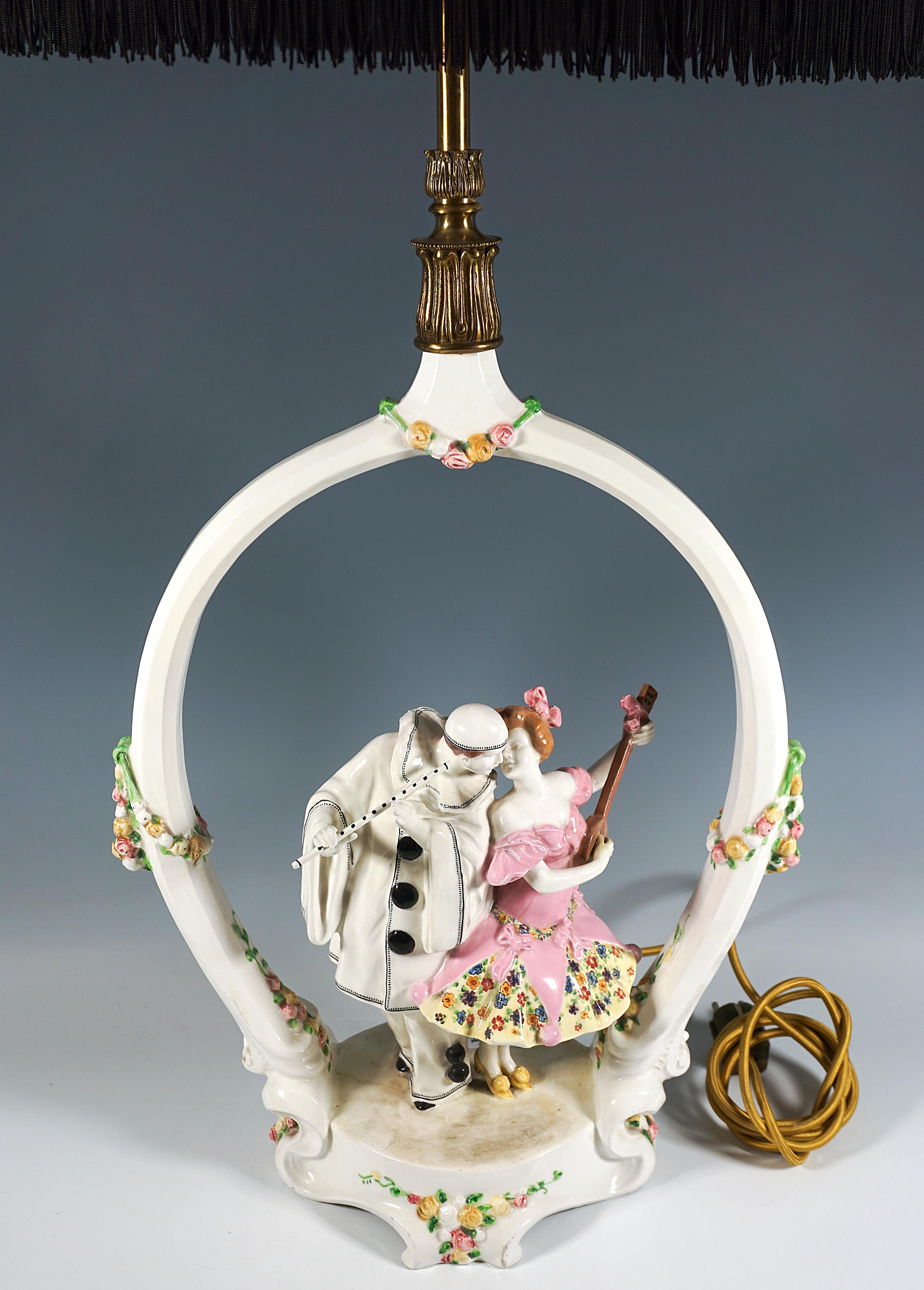 Exceptional rare piece from the Goldscheider ceramic manufactory:
Pierrot with flute and Pierrette with banjo facing each other, standing under an arch decorated with delicate flower garlands and playing music, Pierrot in a white suit with black