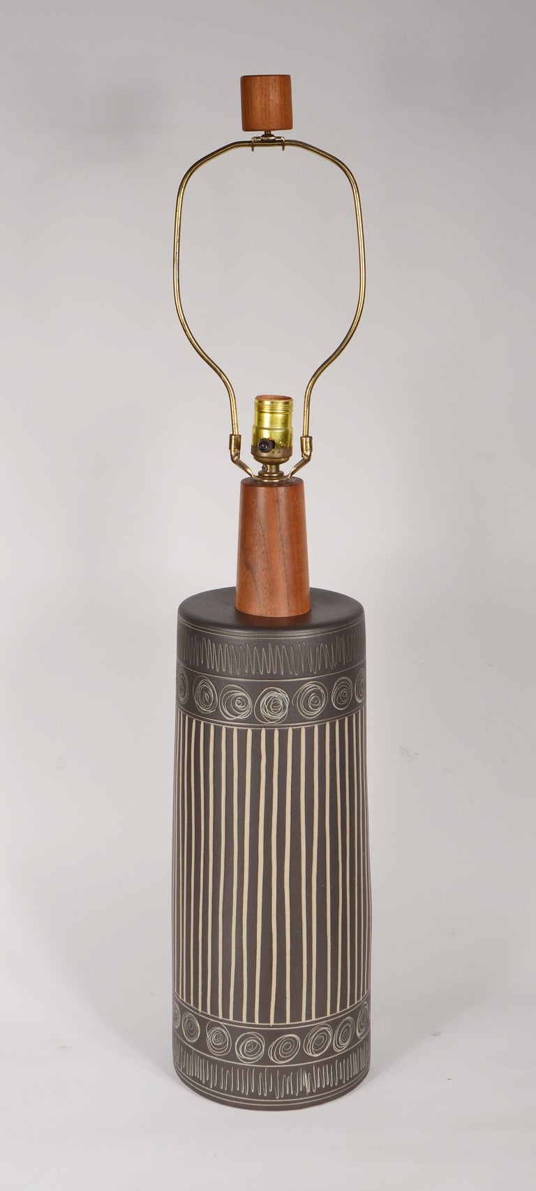 Ceramic table lamp by Gordon & Jane Martz for Marshall Studios. This lamp has a satin dark brown glaze with incised designs. This has the original walnut finial and wiring. We can rewire this at no charge if you would like. Height given is with the