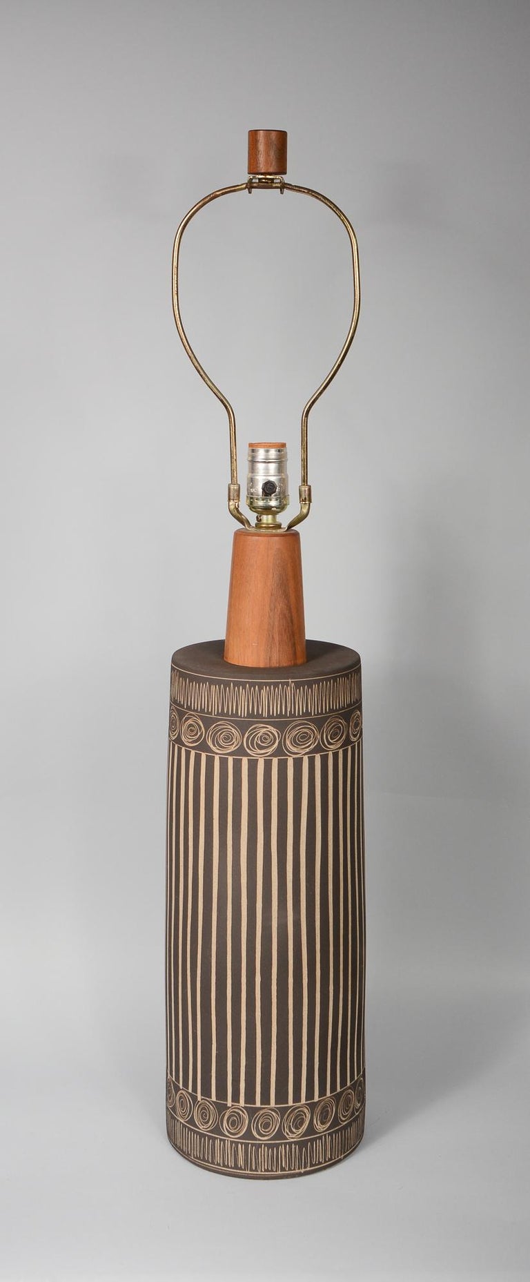 Ceramic table lamp by Gordon & Jane Martz for Marshall Studios. This lamp has a flat brown glaze with incised designs. The glaze has a texture of very fine sand. This has the original walnut finial and wiring. We can rewire this at no charge if you