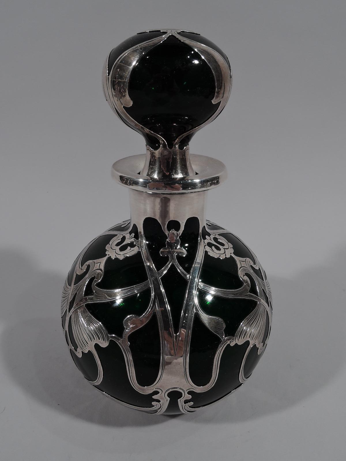 Perfume grande de vidrio verde Art Nouveau de principios de siglo con revestimiento de plata grabada. Fabricado por Gorham en Providence. Globular con borde evertido. Tapón de bola con tapón corto. Volutas de plata sueltas y entrelazadas con cabezas