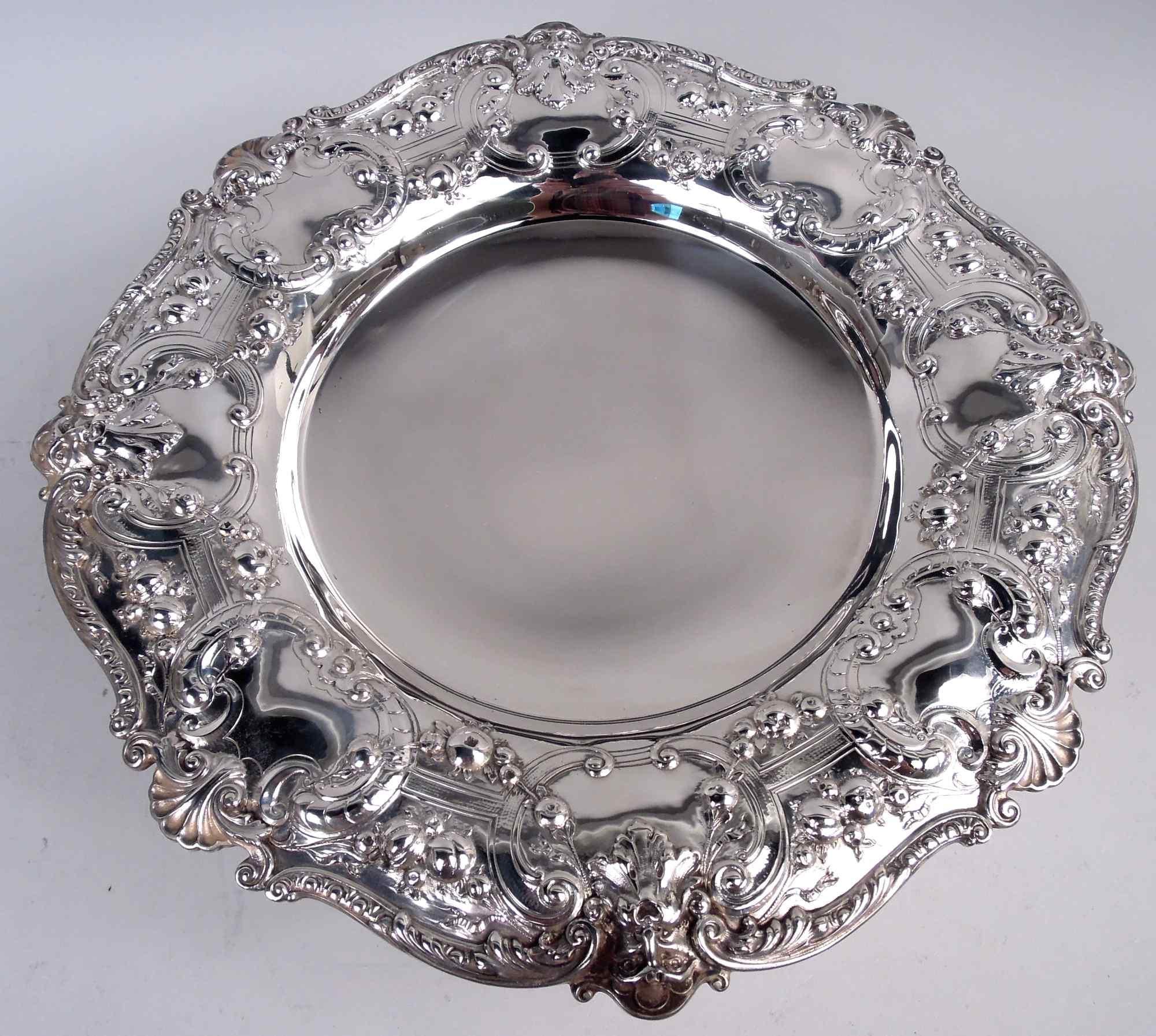 Composta di tazze in argento sterling di Florentine. Prodotto da Gorham a Providence, nel 1910 circa. Pozzo rotondo e liscio; spalla larga con bordo applicato a volute fogliate intervallate da conchiglie a smerlo e maschere fogliate. Supporto