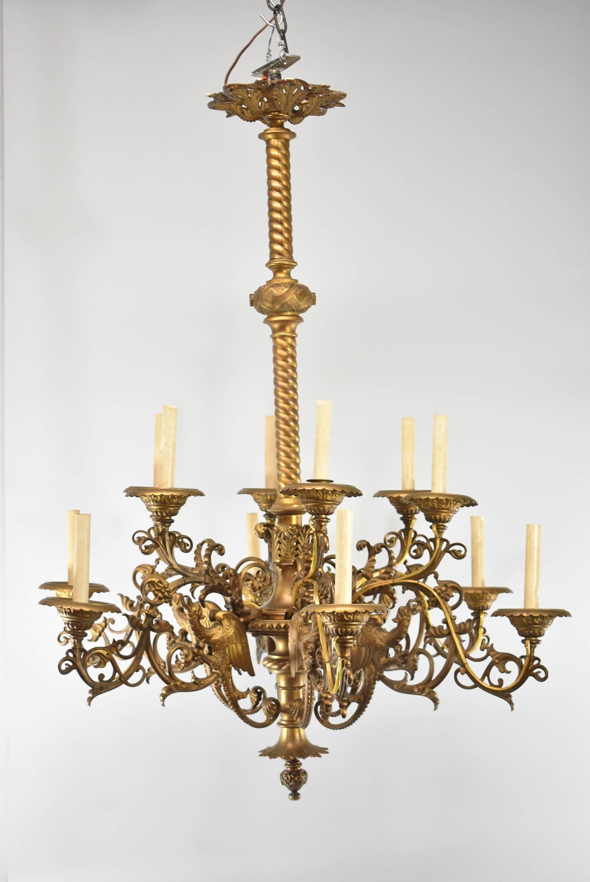 Un magnifique lustre à grande échelle en bronze avec une finition dorée. Elle comporte six bras avec un total de 12 lumières. Chaque bras à volutes est orné d'un oiseau mythique ailé et de raisins. Il est doté d'un centre en corde torsadée. Il est