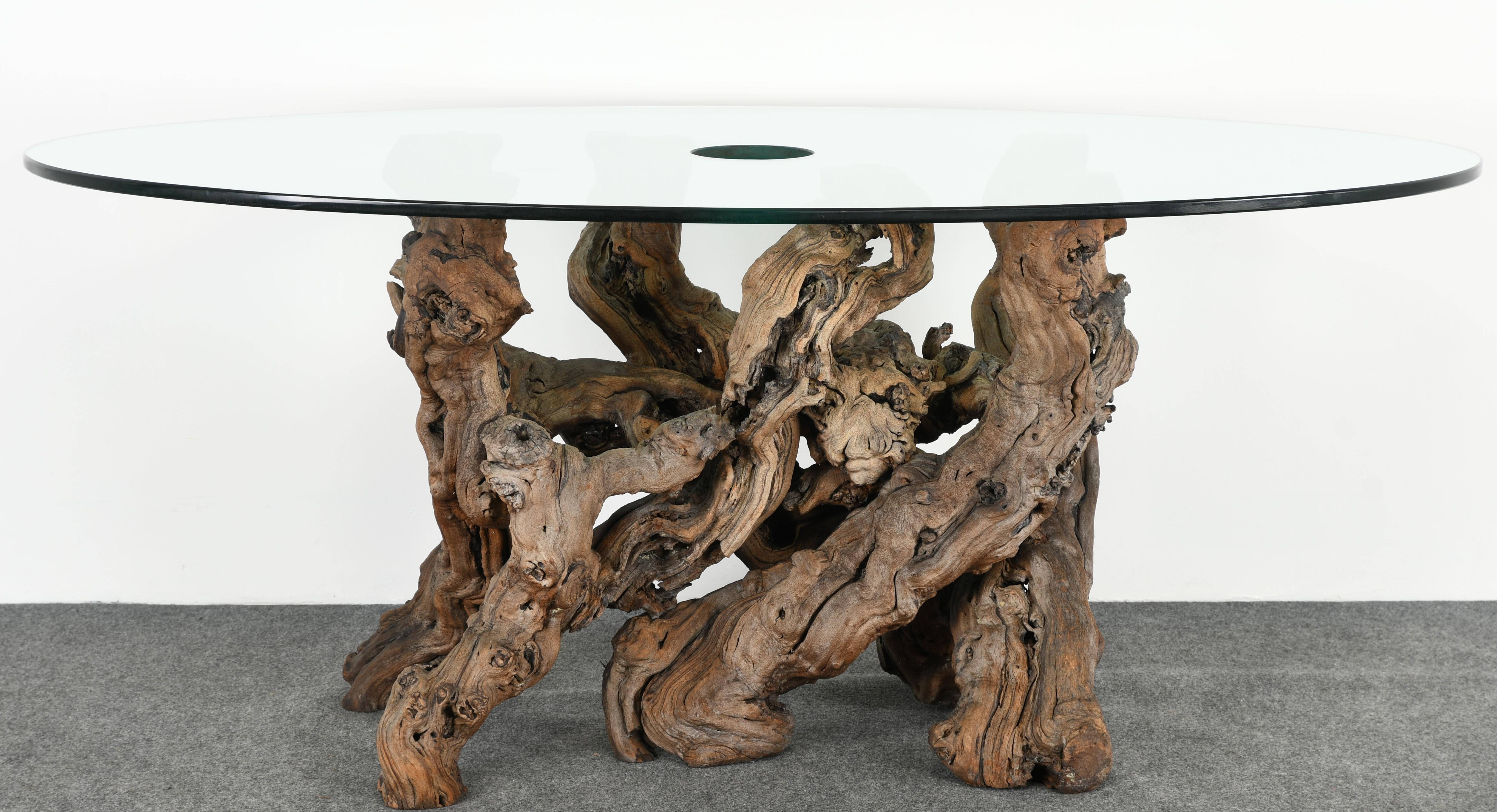 An organic grapevine dining table with a unique glass top wine bottle holder. This is a great table for entertaining and dining with guests. The table is a conversation piece with its old vintage grapevine base. This table comes with the original