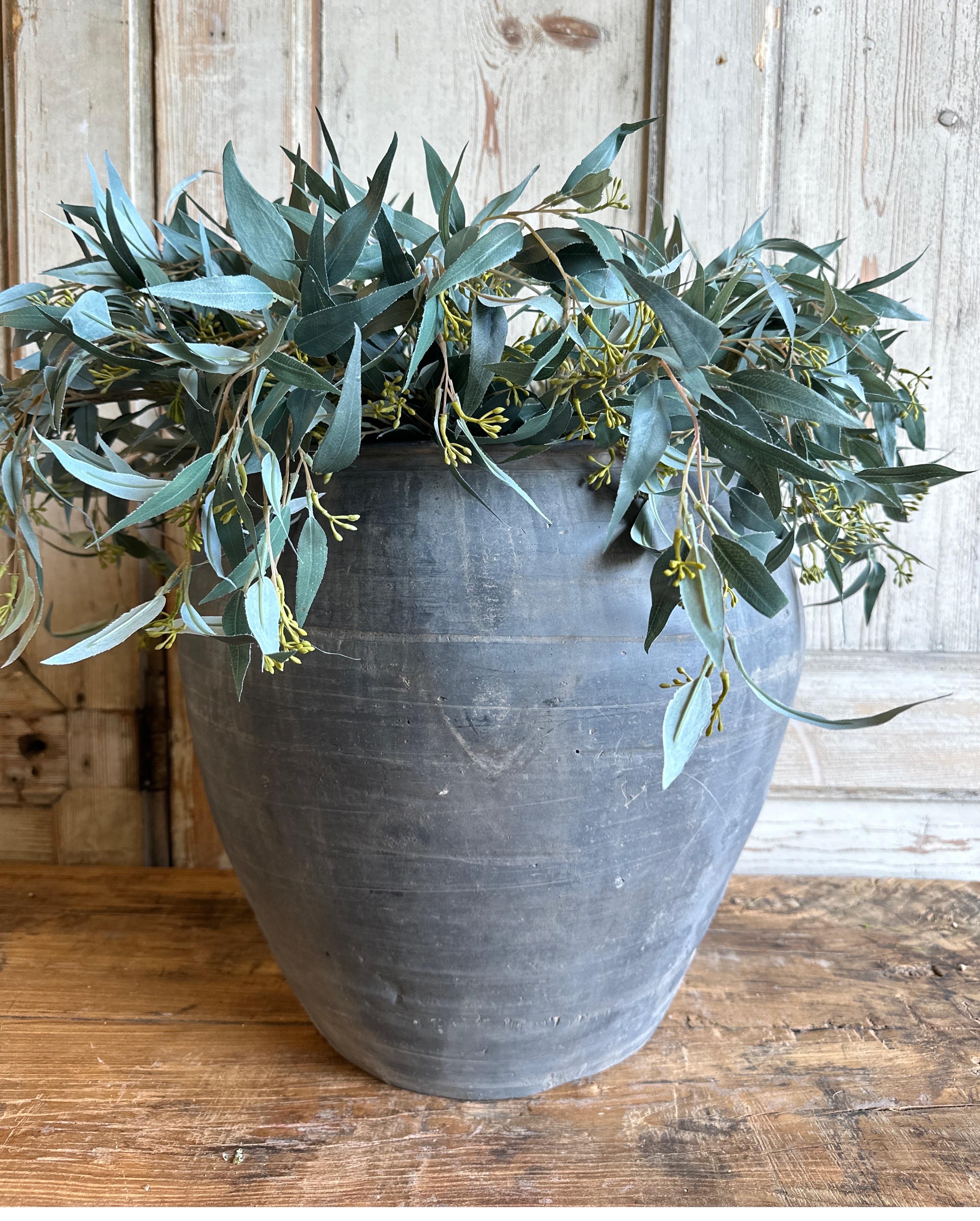 The Grey Croix Pot is a Vintage clay pot that is beautifully colored and authentically worn. The surface of the pot and handle are peeling in places, revealing the original clay below. These qualities give the pot a lived-in appearance and will