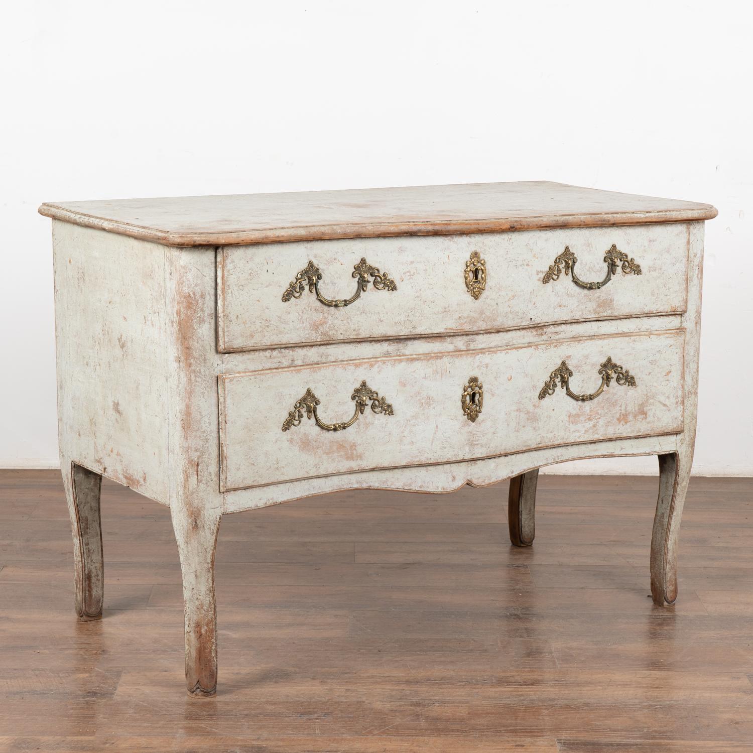 It is the gentle curves that capture one's attention in this lovely large pine chest of two drawers from Italy.
The newer, professionally applied light dove gray painted and distressed finish has a soft, pale blue undertone which fits the age and