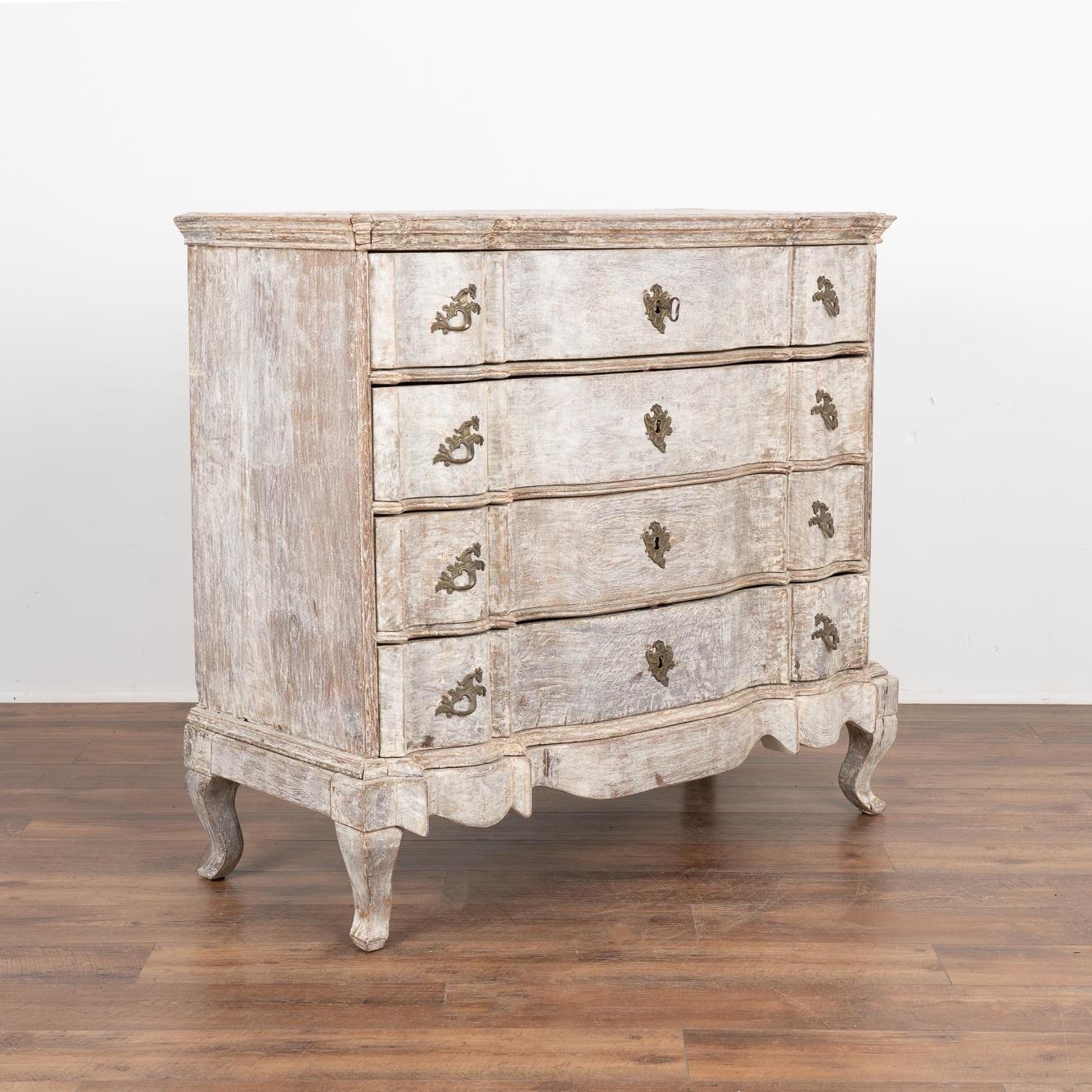 This large antique rococo chest of four drawers features a serpentine front, brass hardware pulls and rests on cabriolet feet.
It has been given an exceptional new professional gray layered painted finish with white undertones. It has been lightly